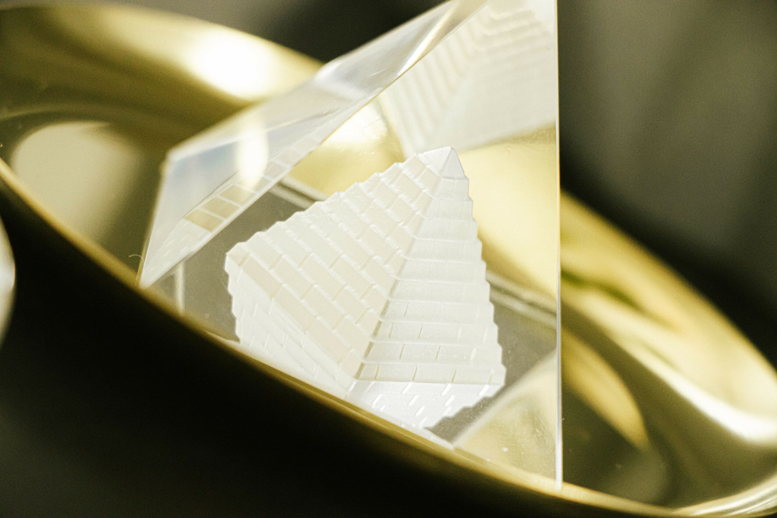 Close-up of a stack of white, rectangular objects with textured surfaces, inside a reflective metallic container.