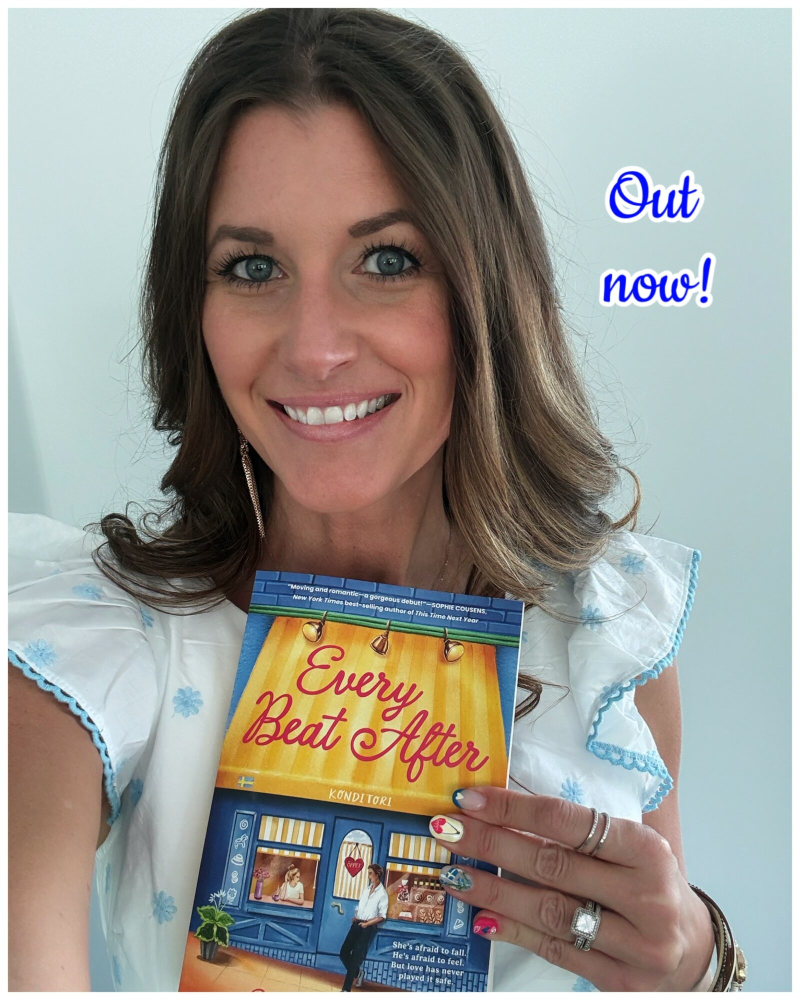 Woman smiling holding a book titled 'Every Beat of My Heart' with text 'Out now!' in blue.