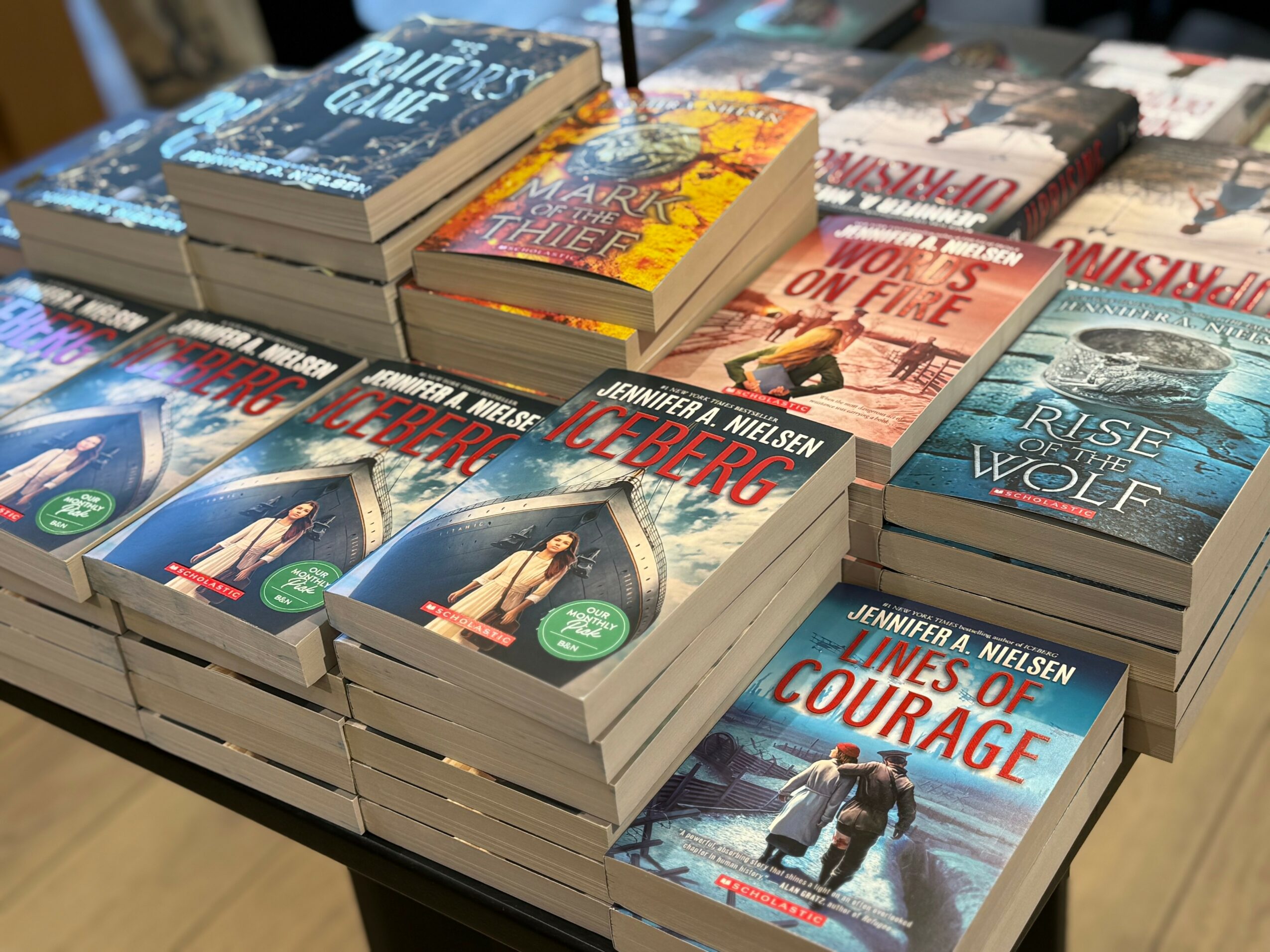 Stacked books on a table, including titles like 'Lines of Courage' and 'Rise of the Wolf'.