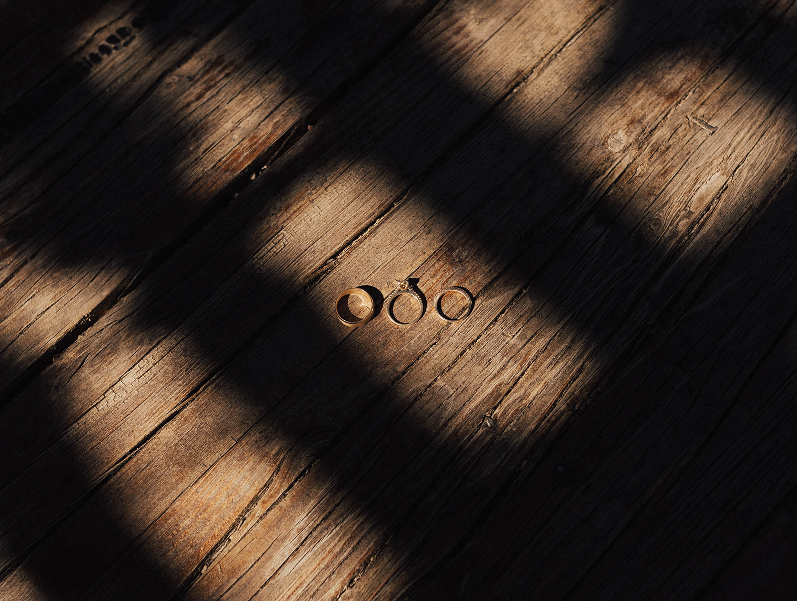 Three small objects on a wooden surface with shadows cast across them, creating a pattern of light and dark areas.