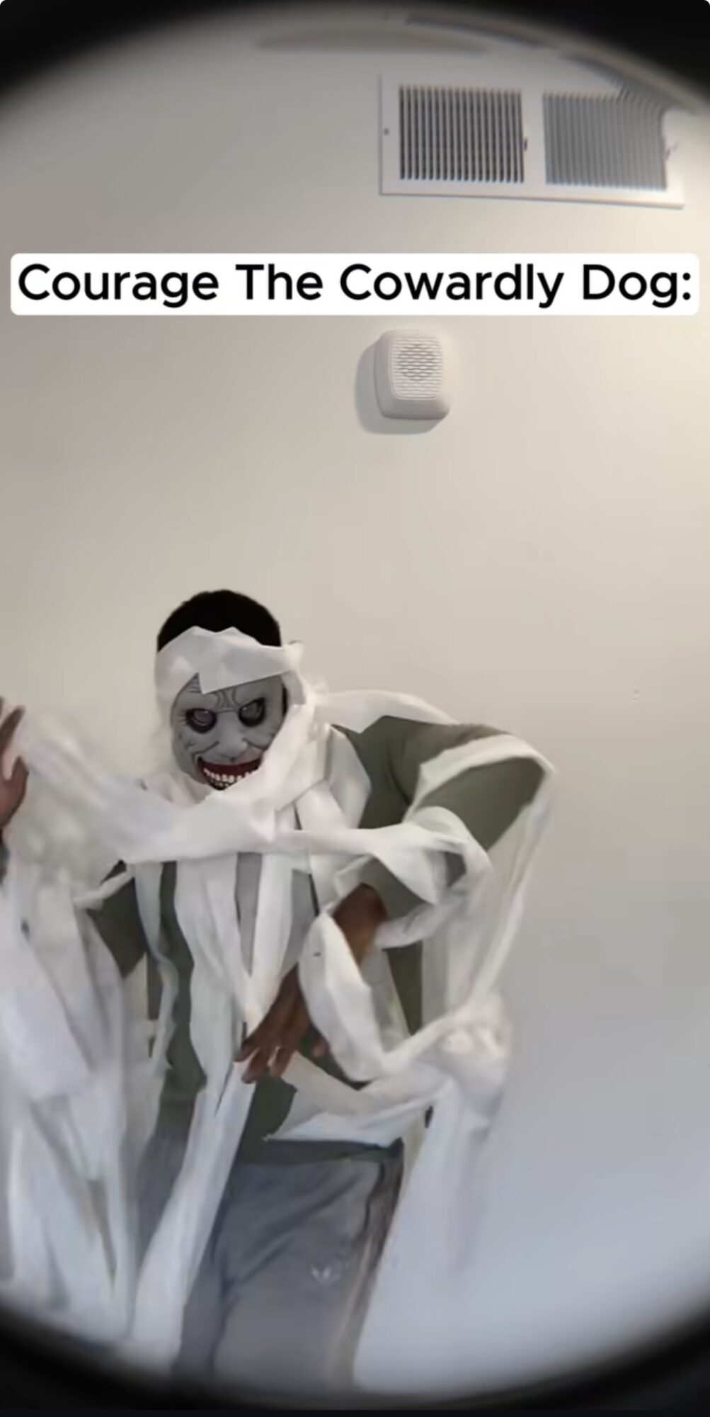Person dressed as a mummy with face paint, standing against a white wall, with text reading 'Courage The Cowardly Dog'.