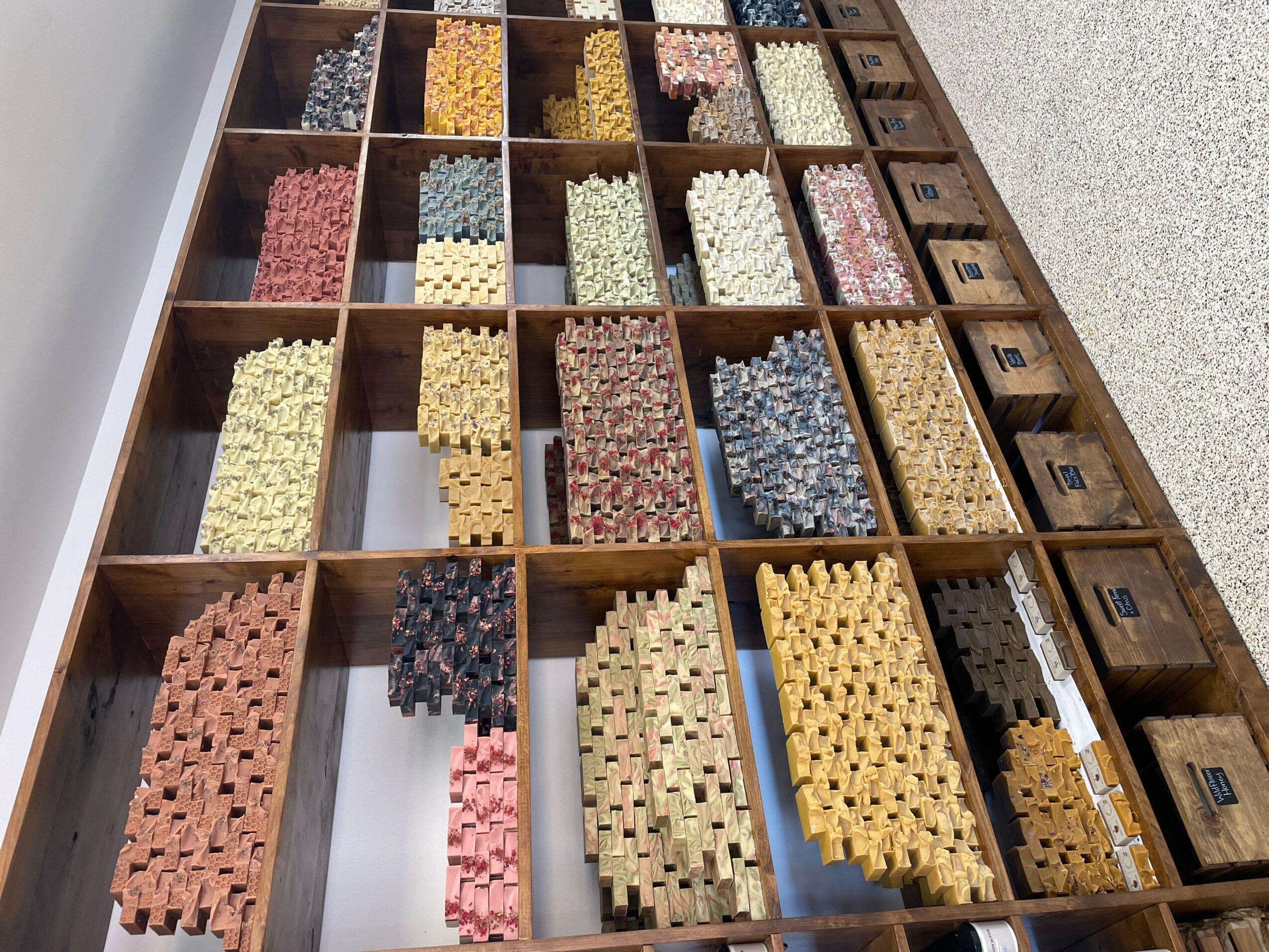 Wooden drawer with compartments filled with colorful small building blocks, viewed from above.