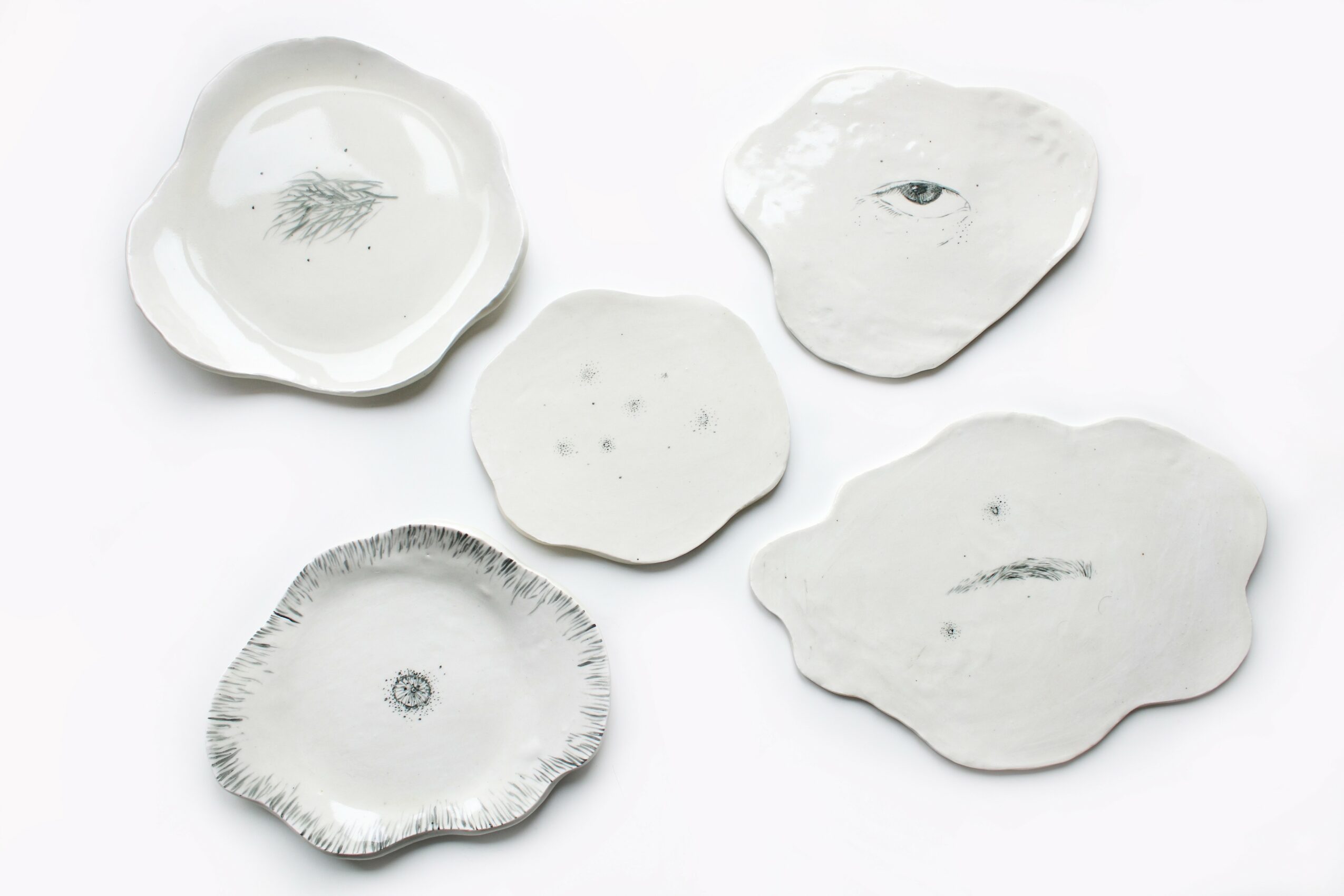 Five white ceramic dishes with irregular shapes and subtle patterns, arranged on a white background.