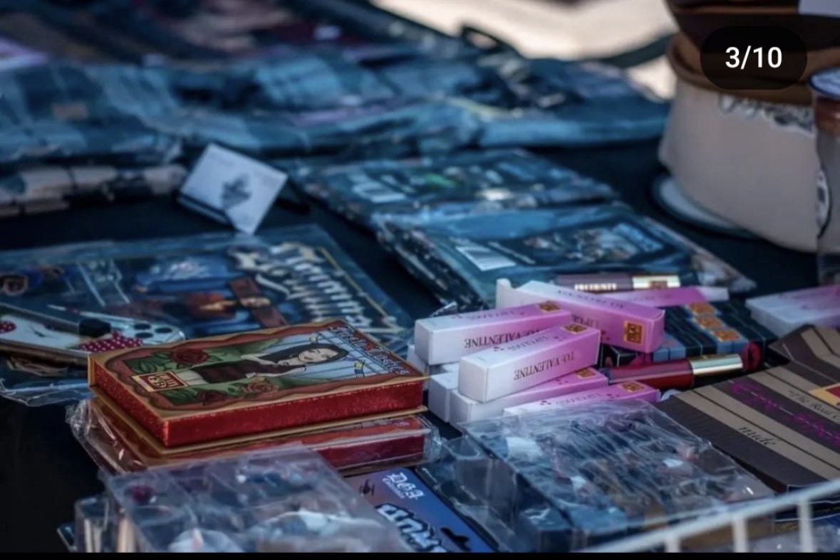 Table with various packaged items, including pink and white boxes, blue packages, and a red box, displayed for sale.