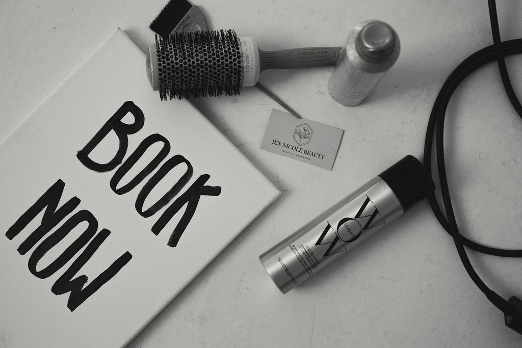Flat surface with a book titled 'NOW BOOK', a hairbrush, a small bottle, a flashlight, and a cable.