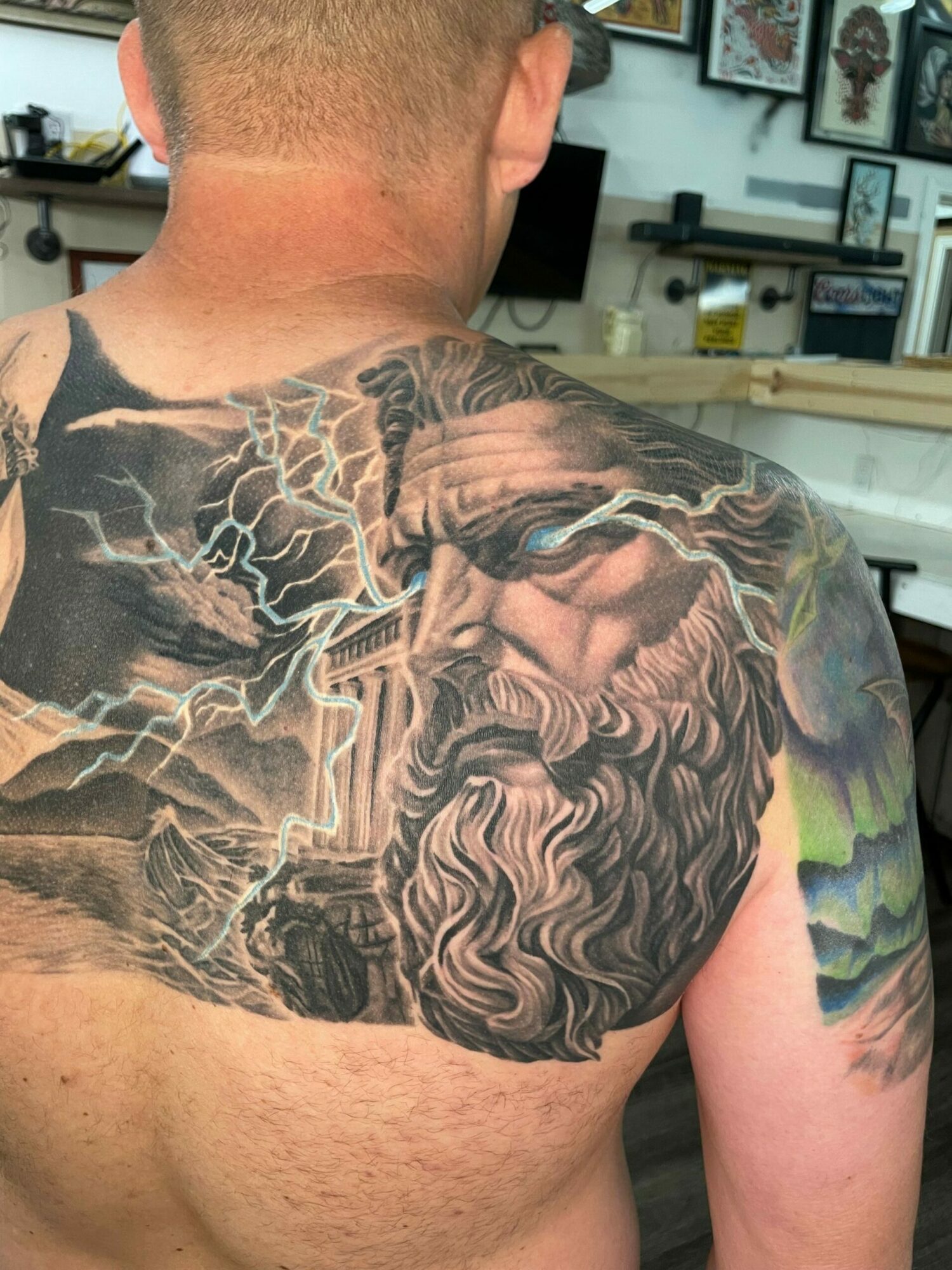Tattoo of a horse with lightning and storm clouds on person's shoulder and upper arm.
