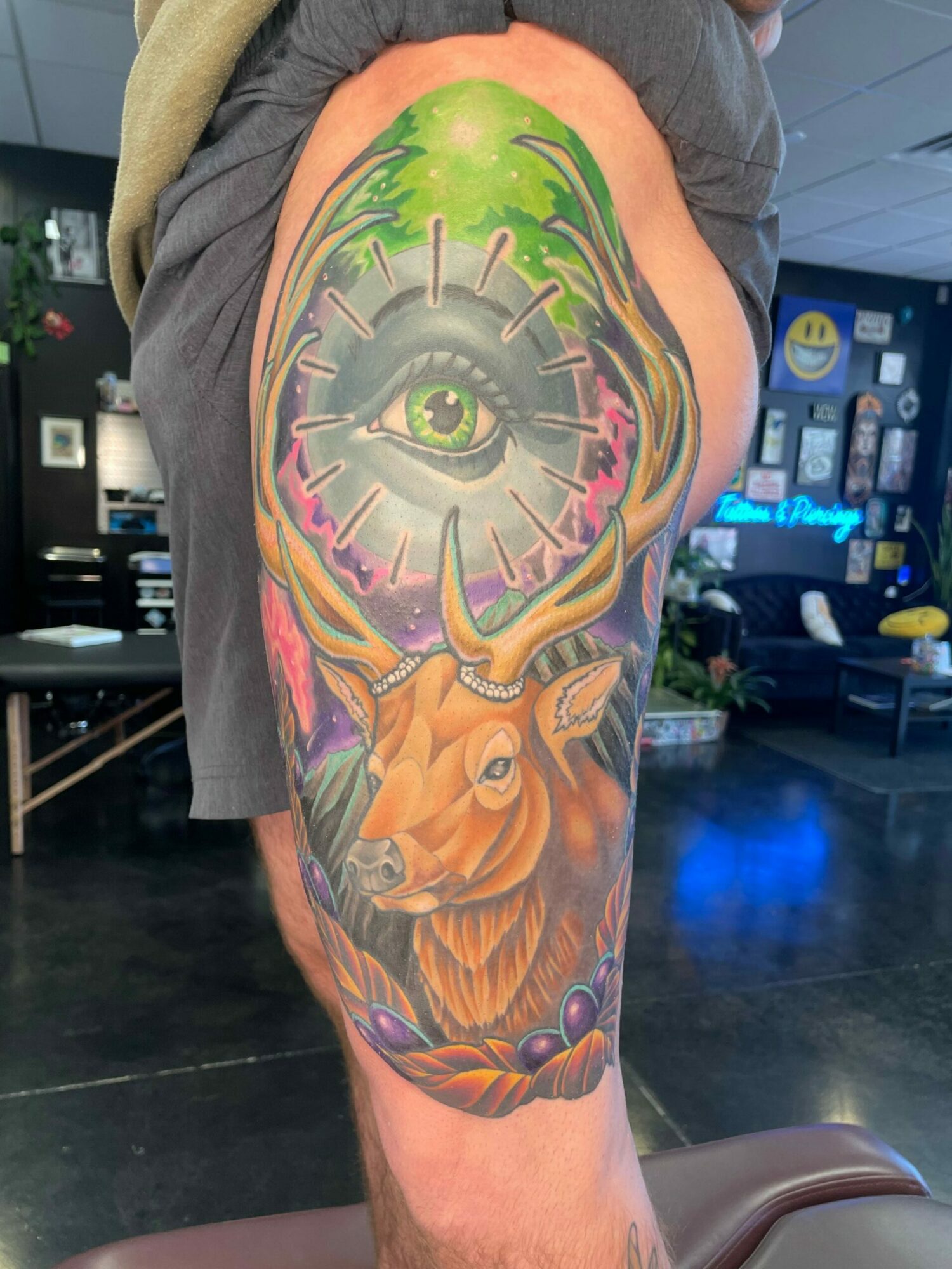 A colorful tattoo sleeve featuring a lion, a mechanical eye, and abstract designs on a person's arm.