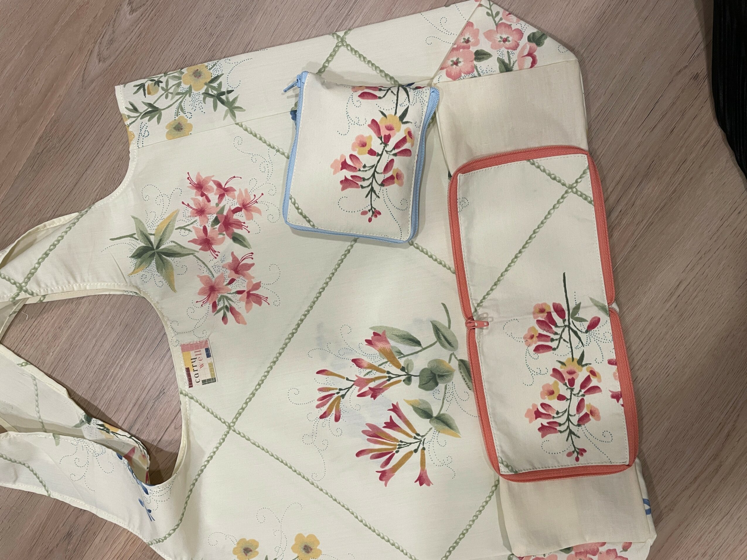 Flat fabric with floral embroidery, including pink, red, and green flowers, and colorful borders, on a wooden surface.