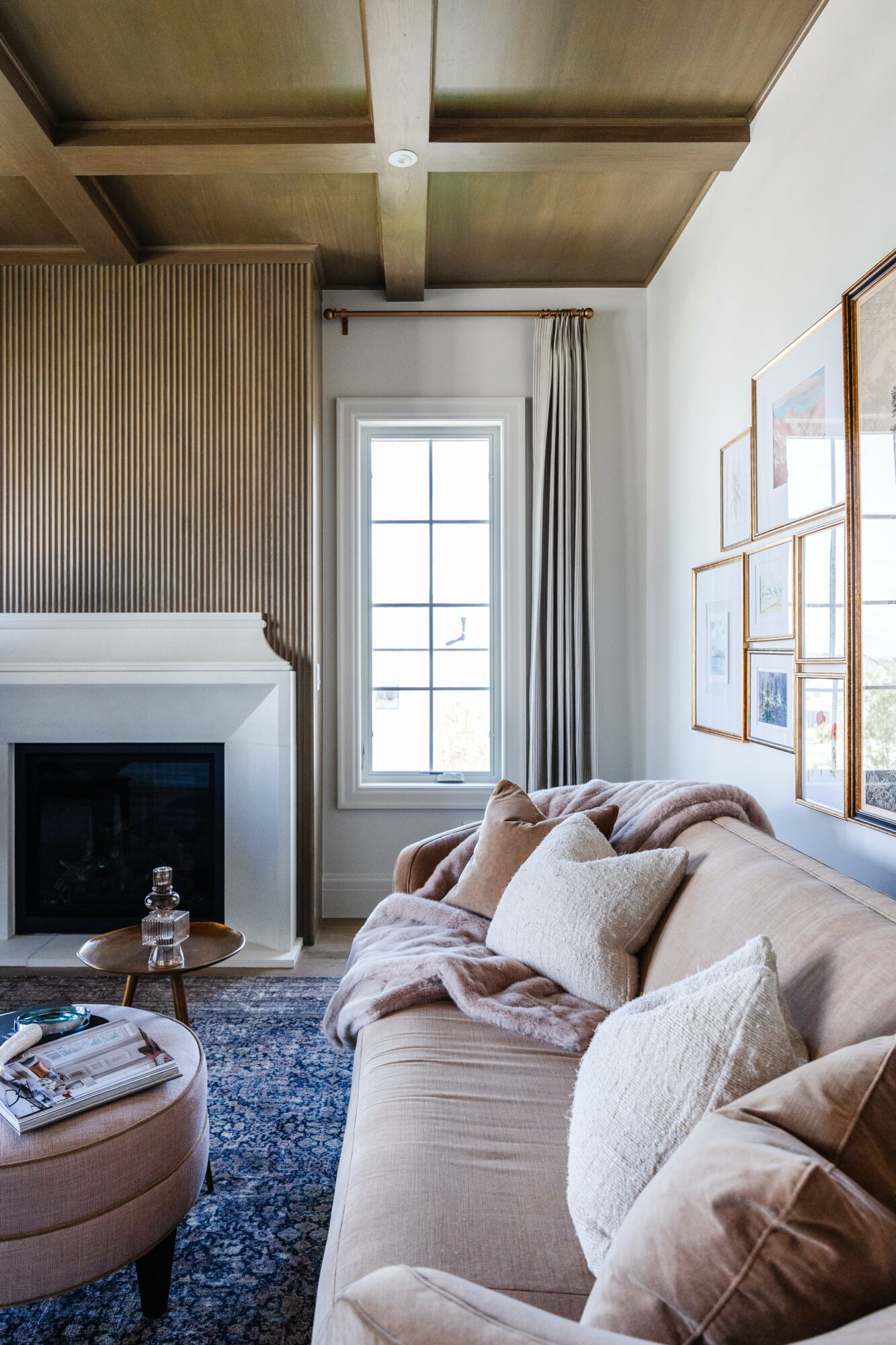 Living room with beige sofa, window with curtains, fireplace, and framed artwork on wall.