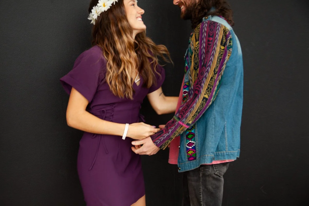 Two people holding hands and smiling at each other against a black background.