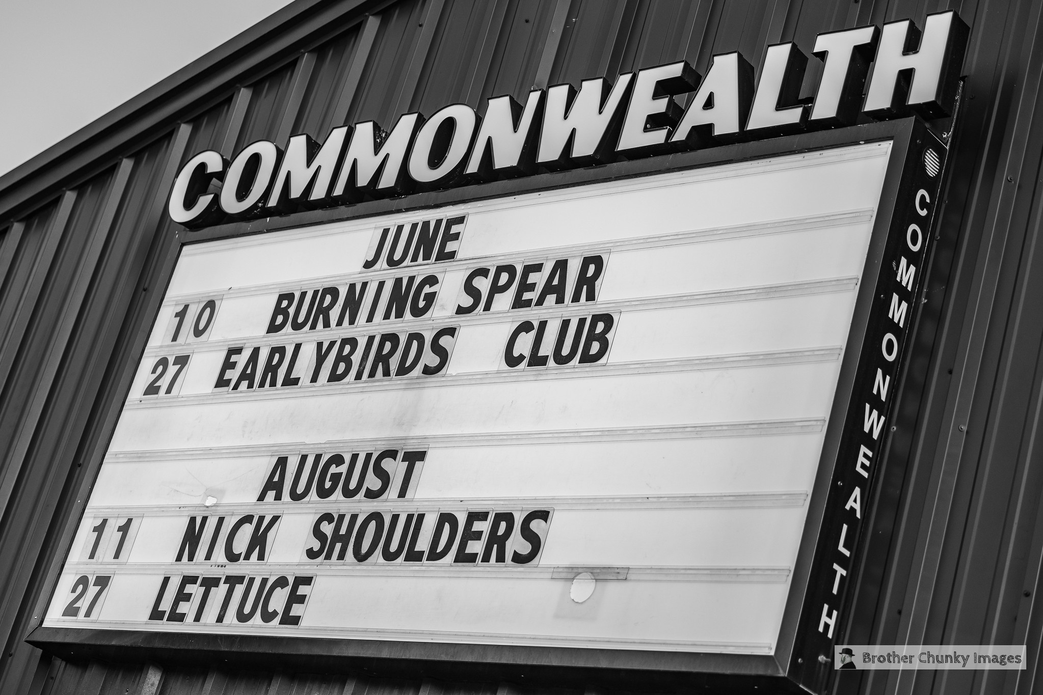 Signboard displaying event dates and names for June and August at Commonwealth, with black background and white text.