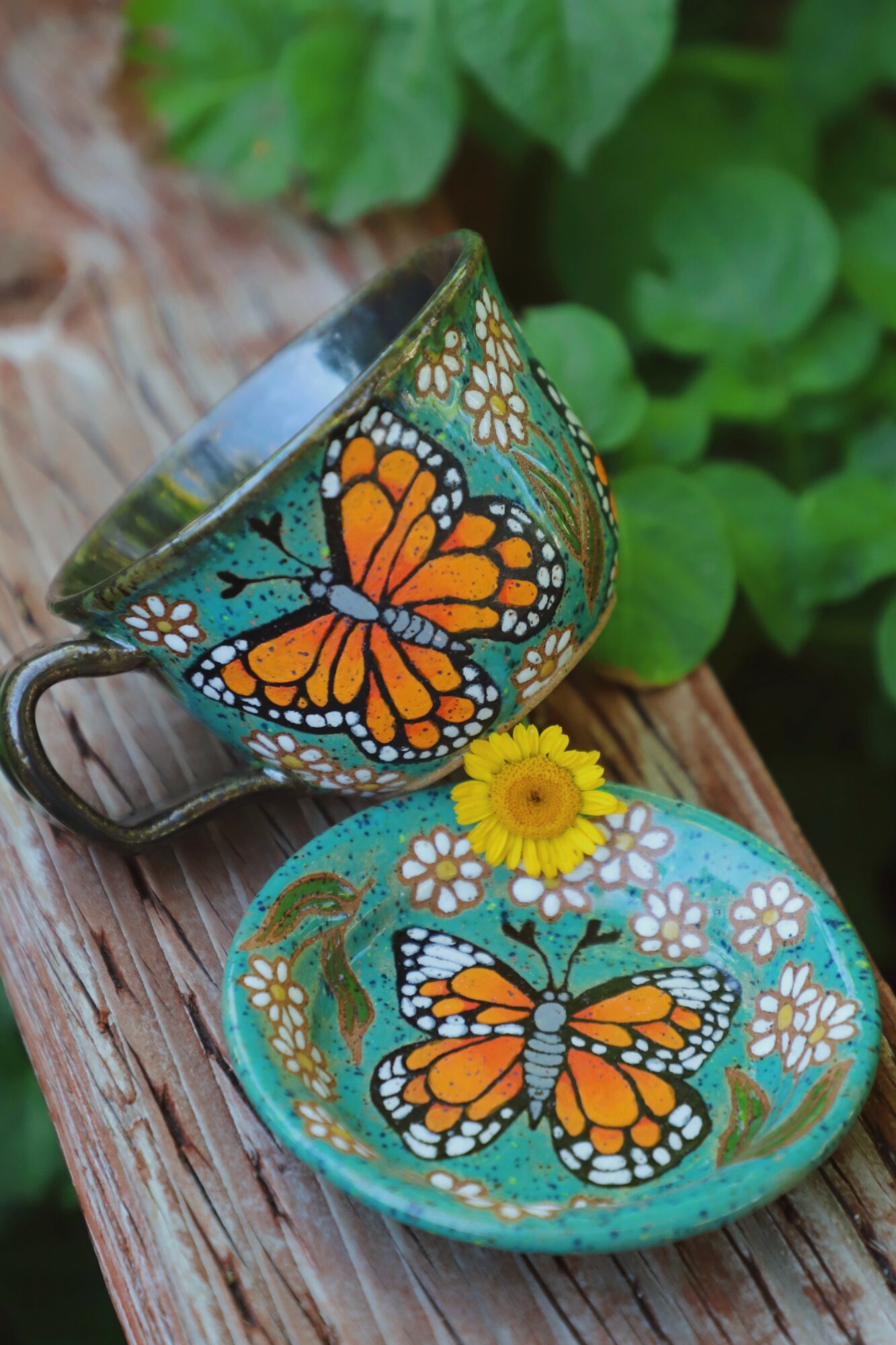 Decorative bowl with butterfly and flower designs, placed on a wooden surface with green leaves in background.