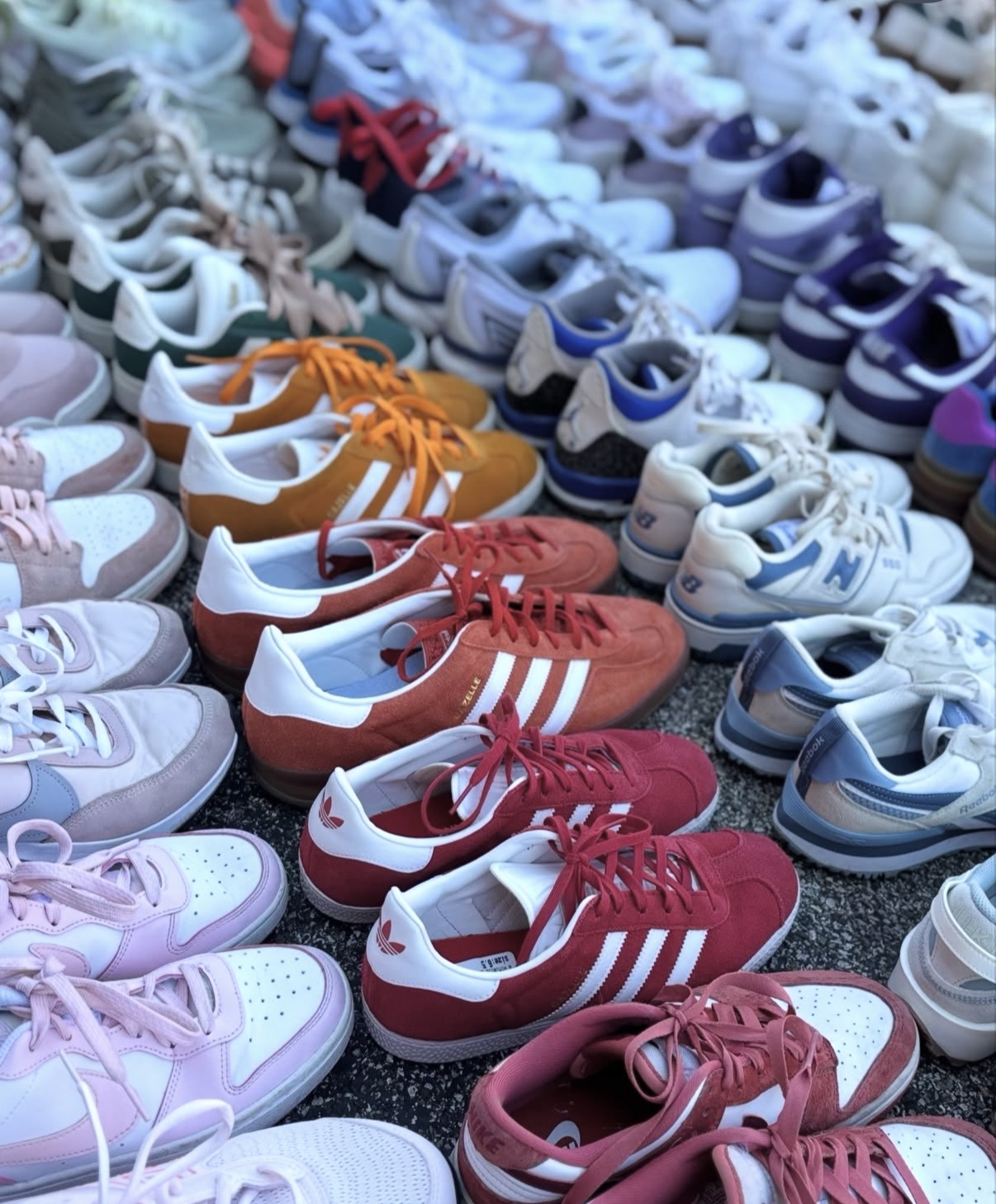 Multiple pairs of colorful sneakers arranged in rows on a surface, with various colors including red, purple, blue, and pink.