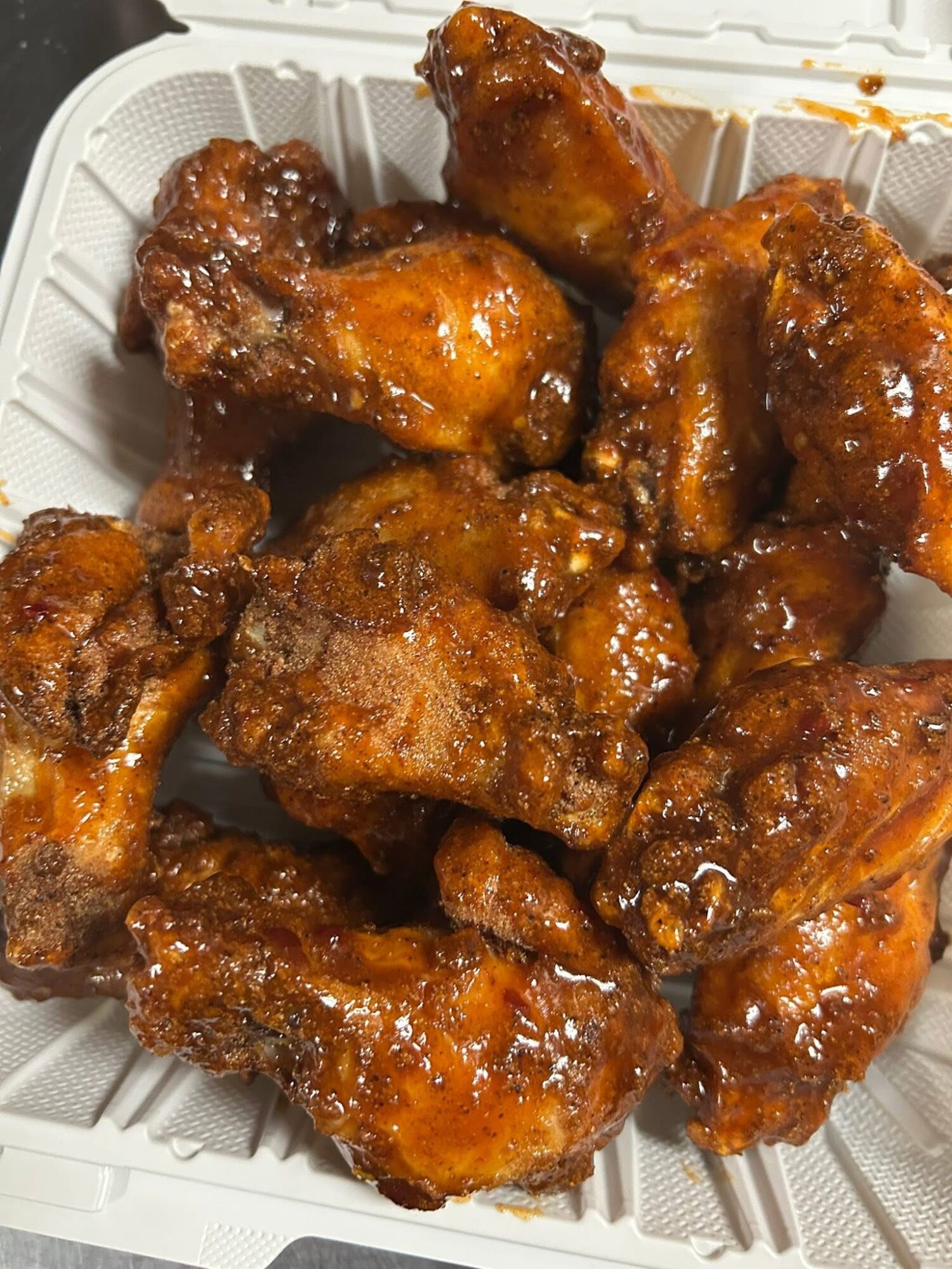 Fried chicken wings coated in sauce in a white container