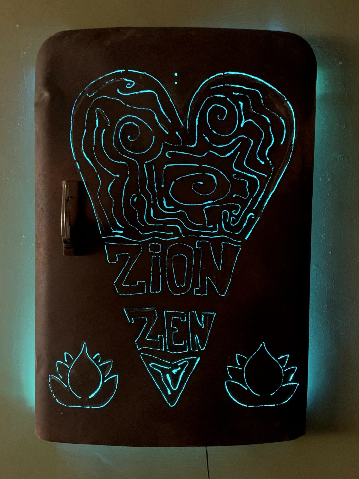 Heart shape with maze pattern, the words ZION and ZEW, and two lotus flowers at the bottom.