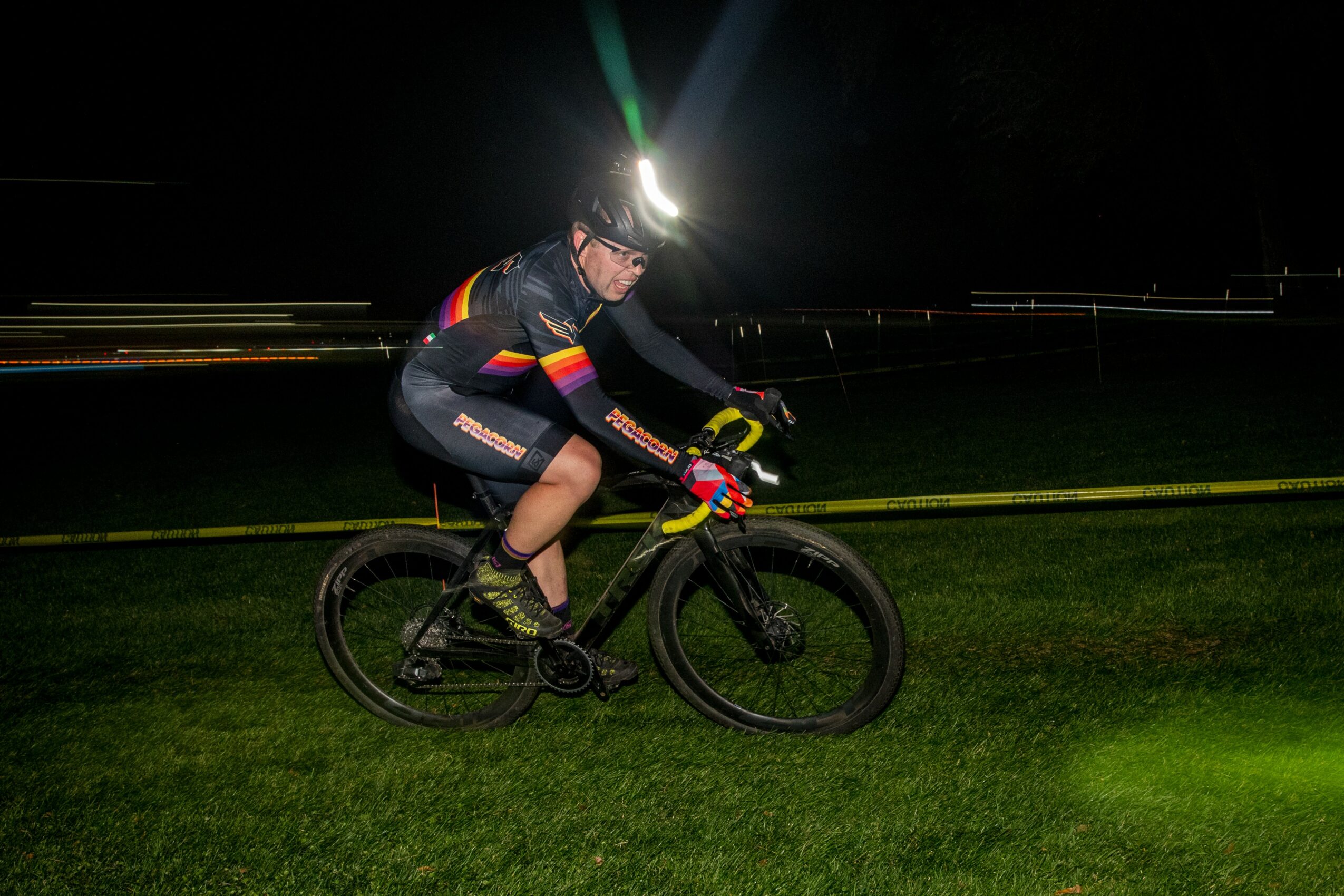 Cyclist riding a mountain bike at night with a headlamp, on a grassy area, motion blur in background