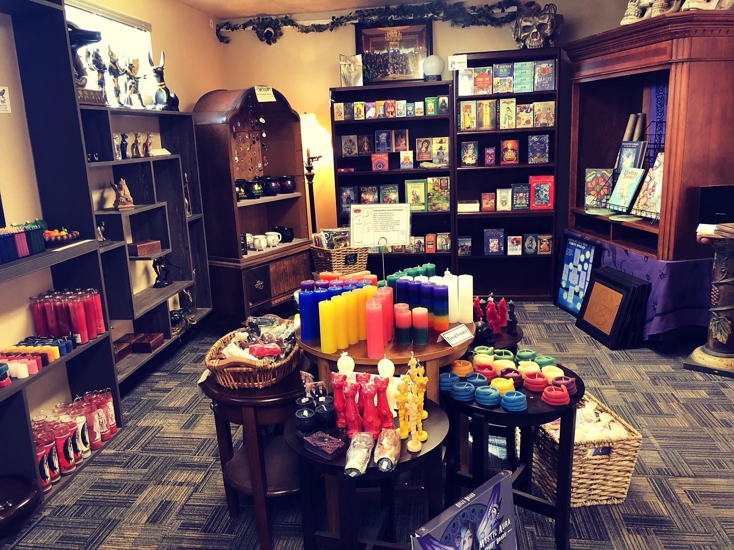 Interior of a store with shelves of books, candles, and decorative items, and a table with colorful candles and gifts.