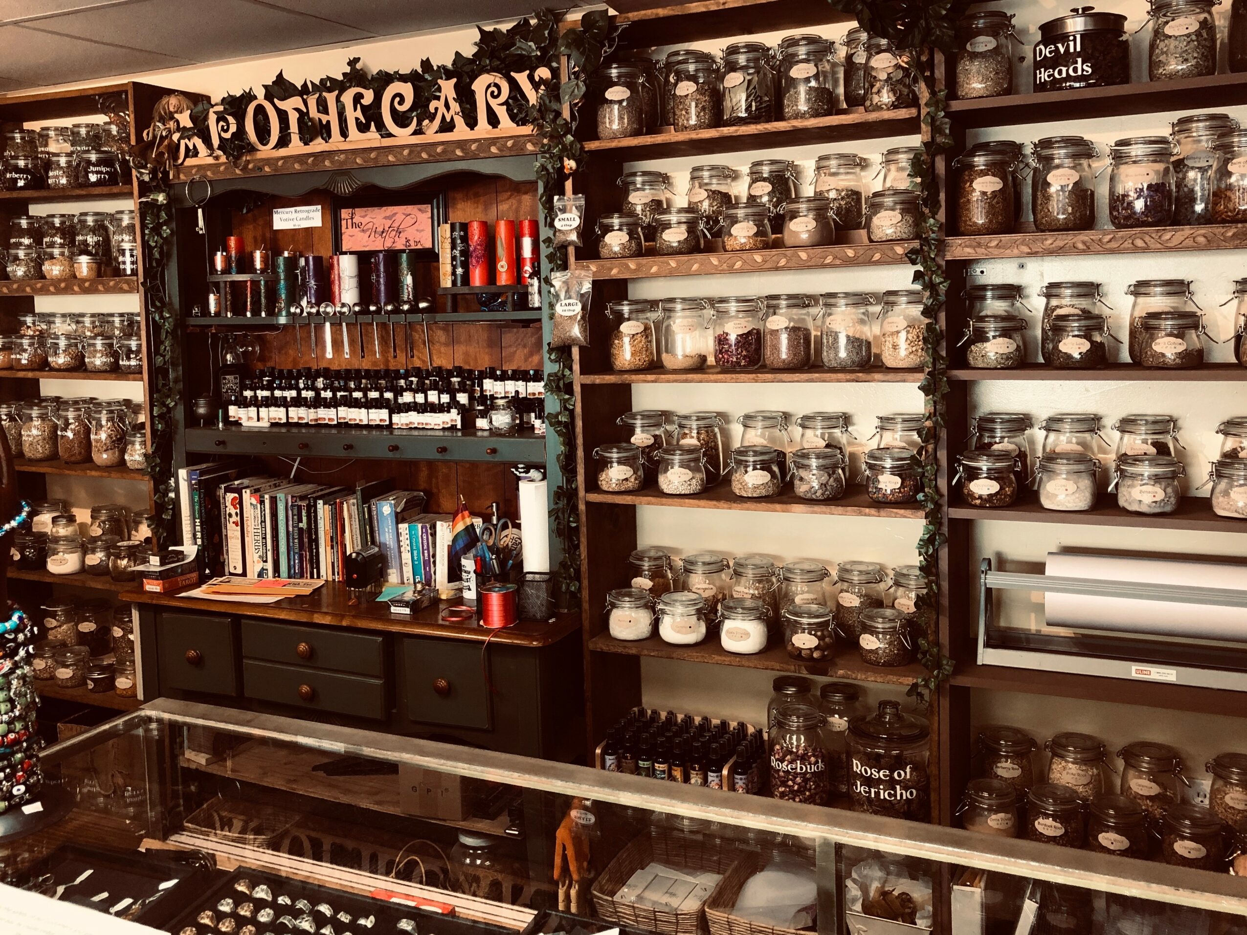 Bookshelves filled with jars and books, with a sign reading 'Potions' at the top, in a cozy room.