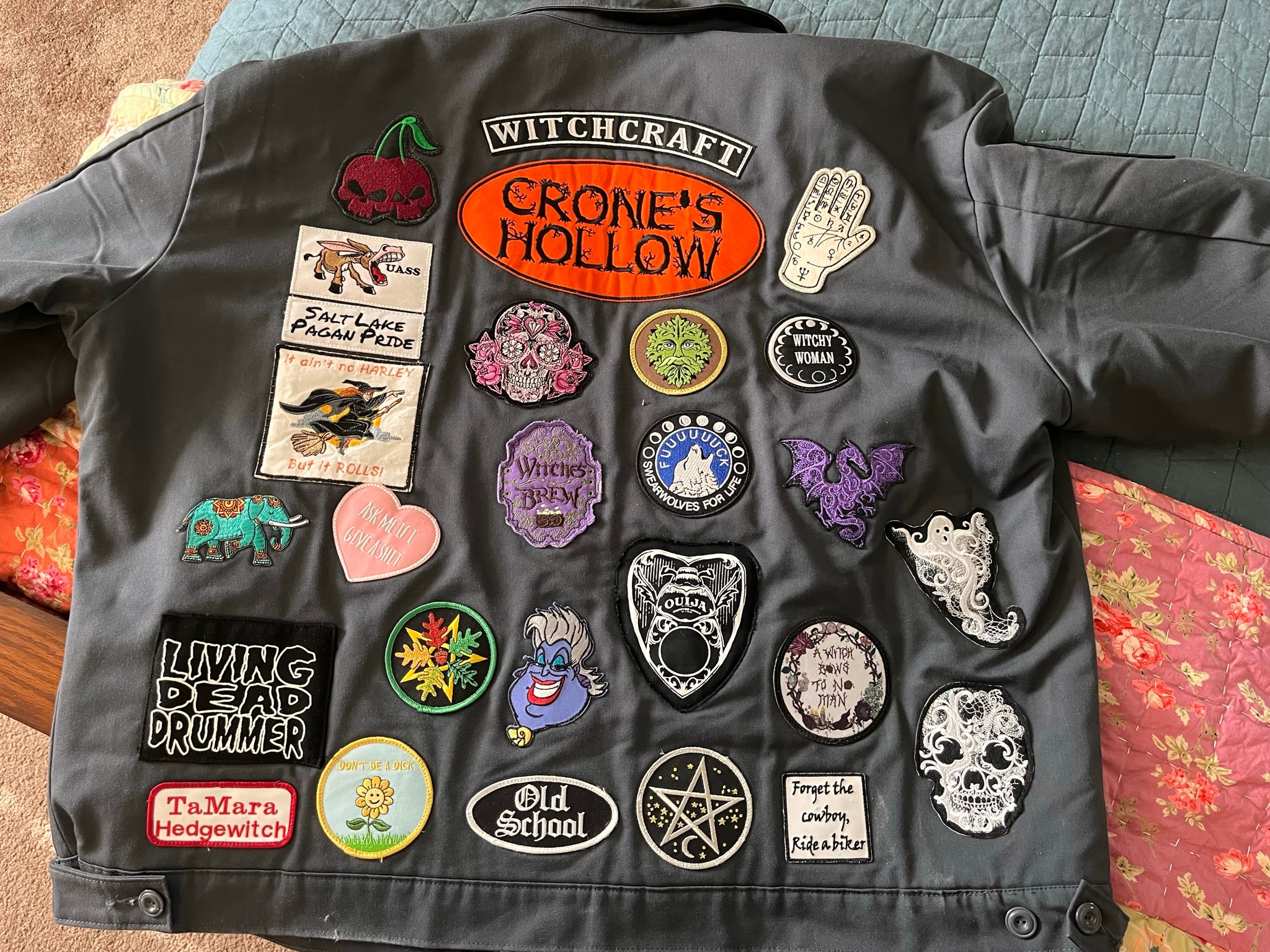 Black jacket with various colorful patches and pins, including a spider, skull, pentagram, and text patches, laid on a surface.