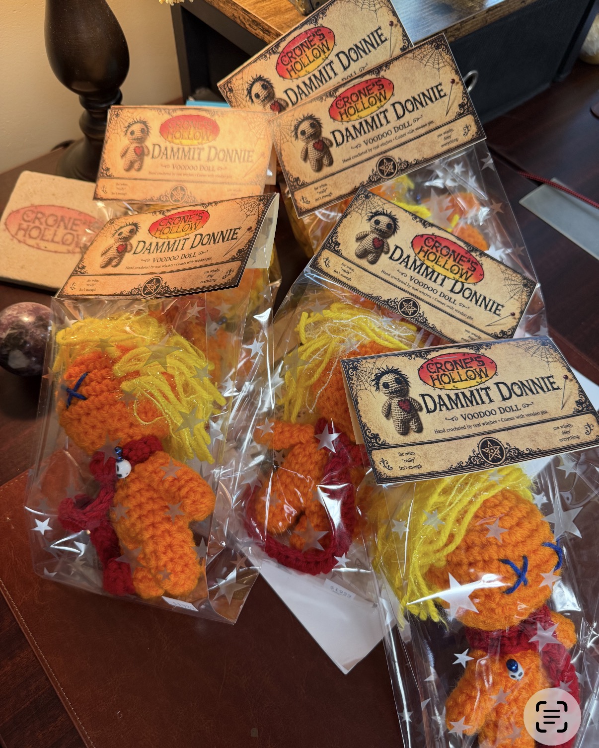 Multiple crocheted animal toys in plastic bags with boxes labeled 'Damn It Donnie' on a wooden surface.