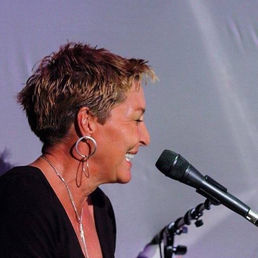 Side view of a smiling woman with short hair speaking into a microphone.