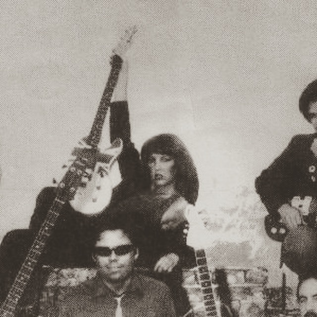 Two women with guitars, one wearing sunglasses, one standing with an arm raised, in black and white.