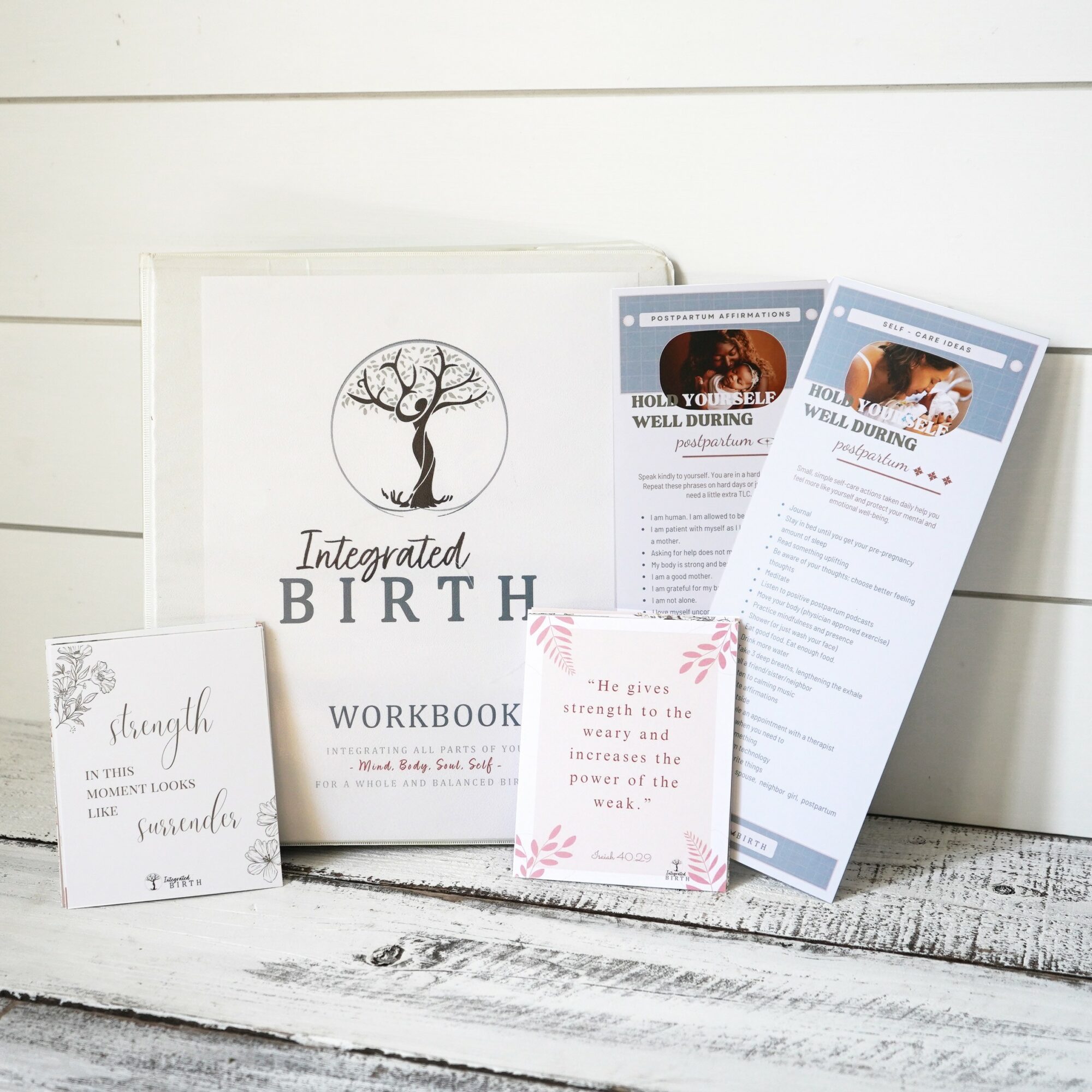 Baby birth workbook, two tickets, and greeting cards on a white wooden surface, with a white background.