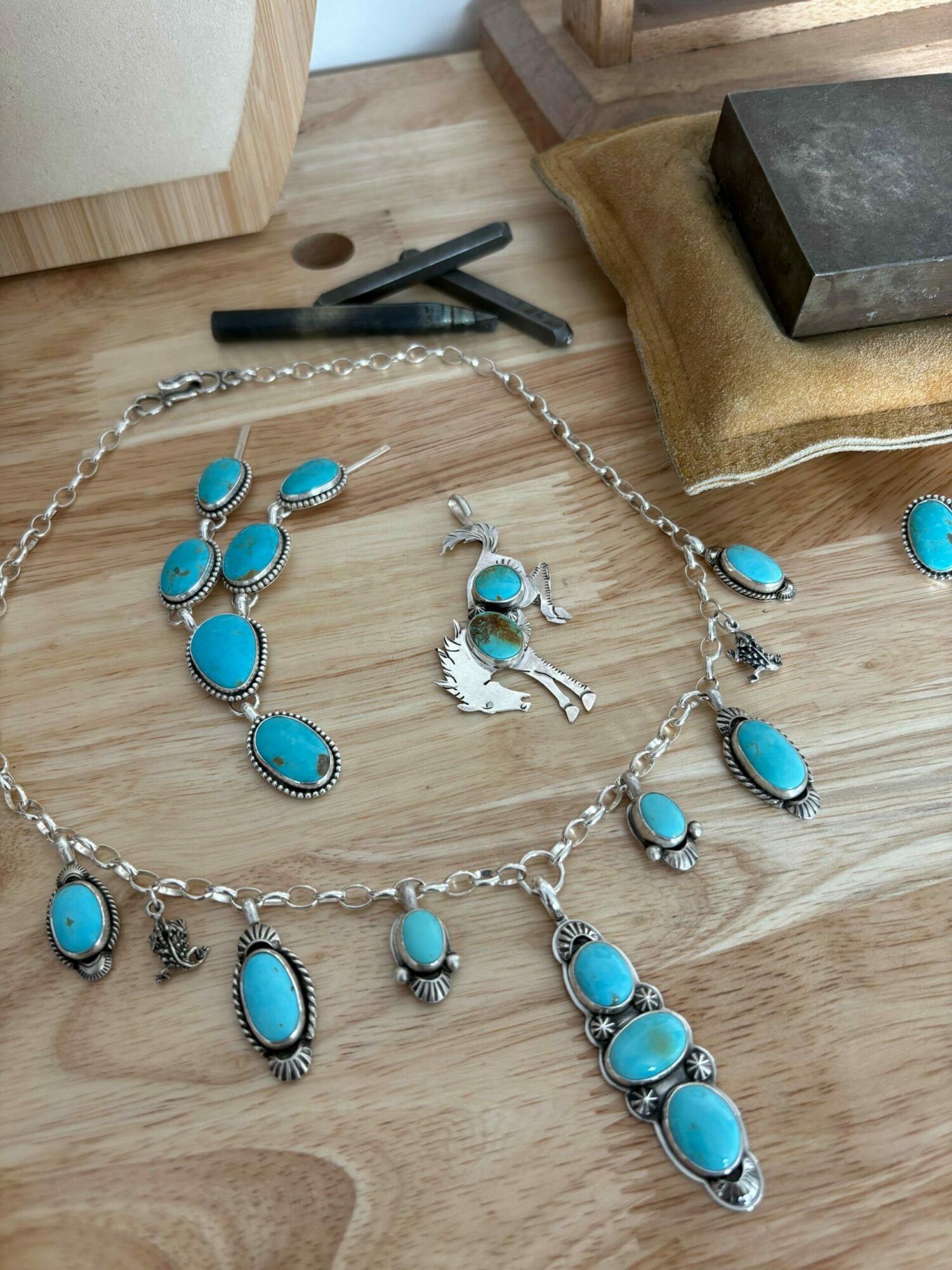 Jewelry set with turquoise stones, including a necklace, bracelet, earrings, and a ring, displayed on a wooden surface.