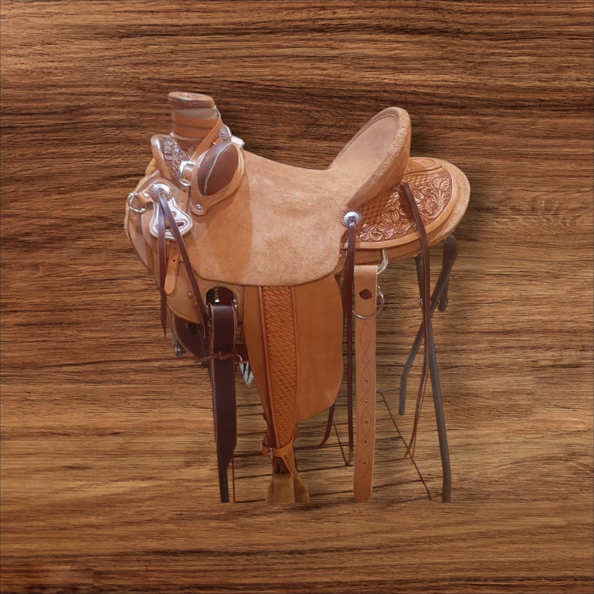 A wooden saddle with leather straps and a glass container on a wooden surface.