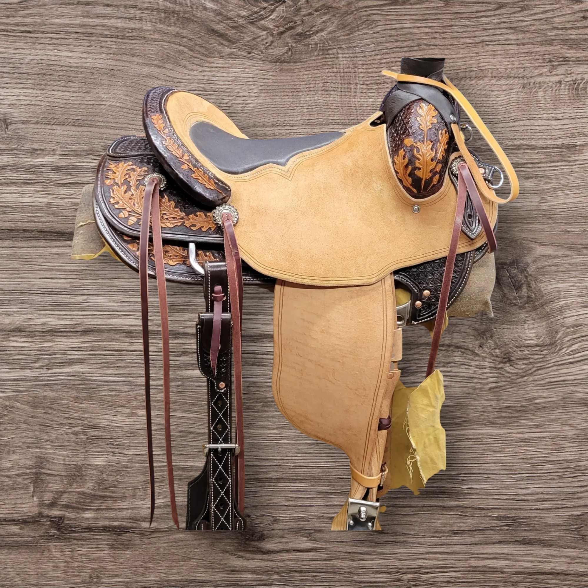 Western saddle with leather straps on a wooden surface.