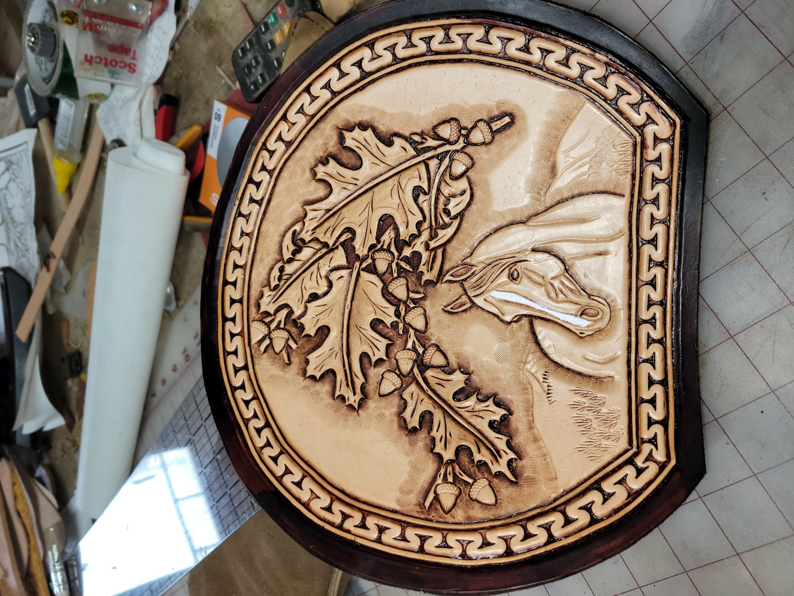 Wooden carved plaque with oak leaf and acorn design, and a bird, framed by Greek key pattern.