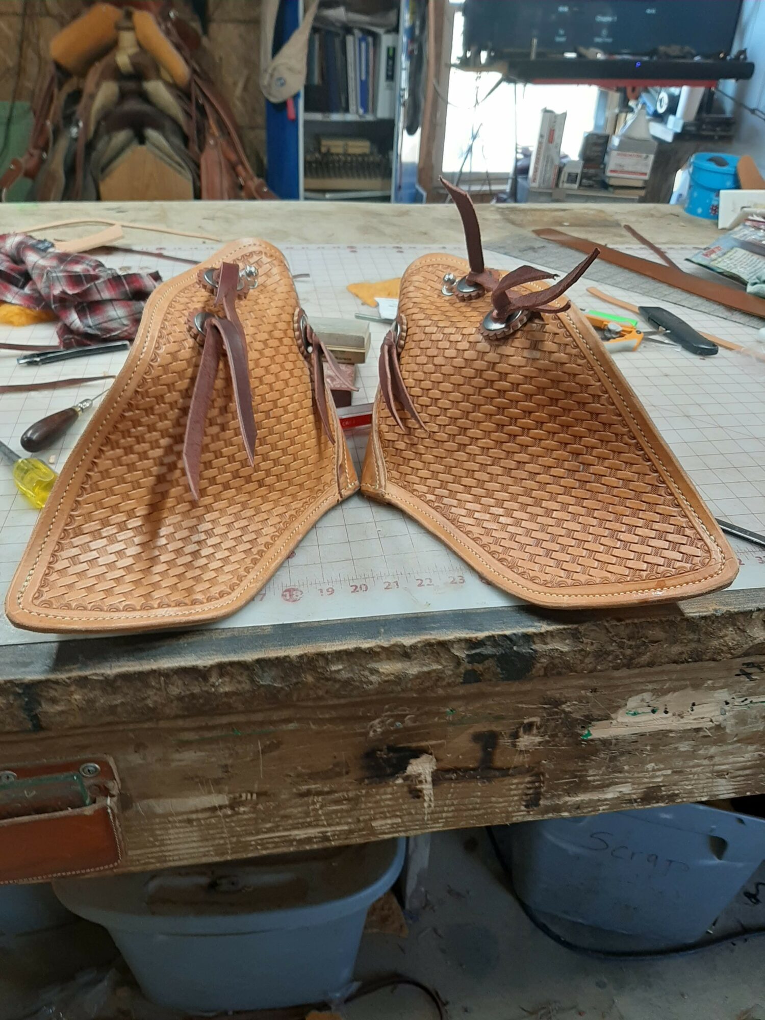 Two woven leather handbags with zippers and handles placed on a workbench in a workshop.