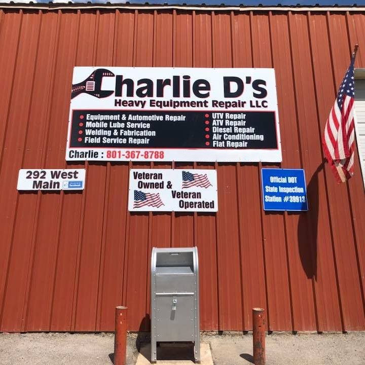 Charlie D's Heavy Equipment Repair LLC sign with services listed, American flag, and address on a red building.