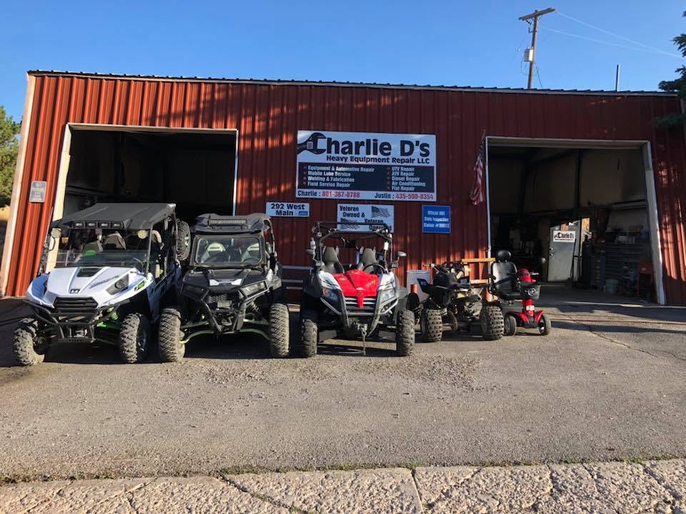 Storefront with off-road vehicles parked outside, red building with signs, blue sky, and a paved ground.