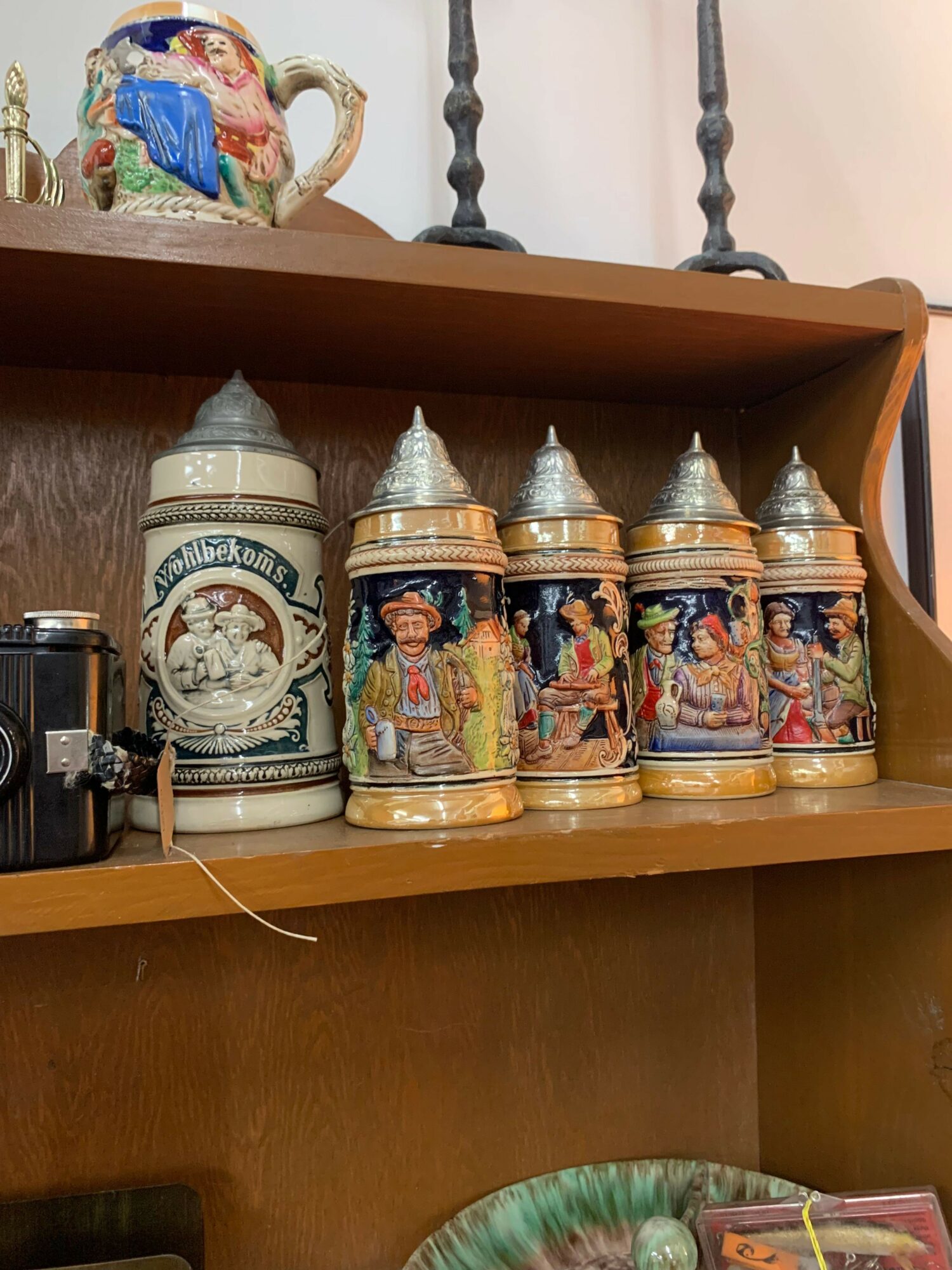 Shelf with religious figurines and a decorative container, with a colorful ceramic item in the background.
