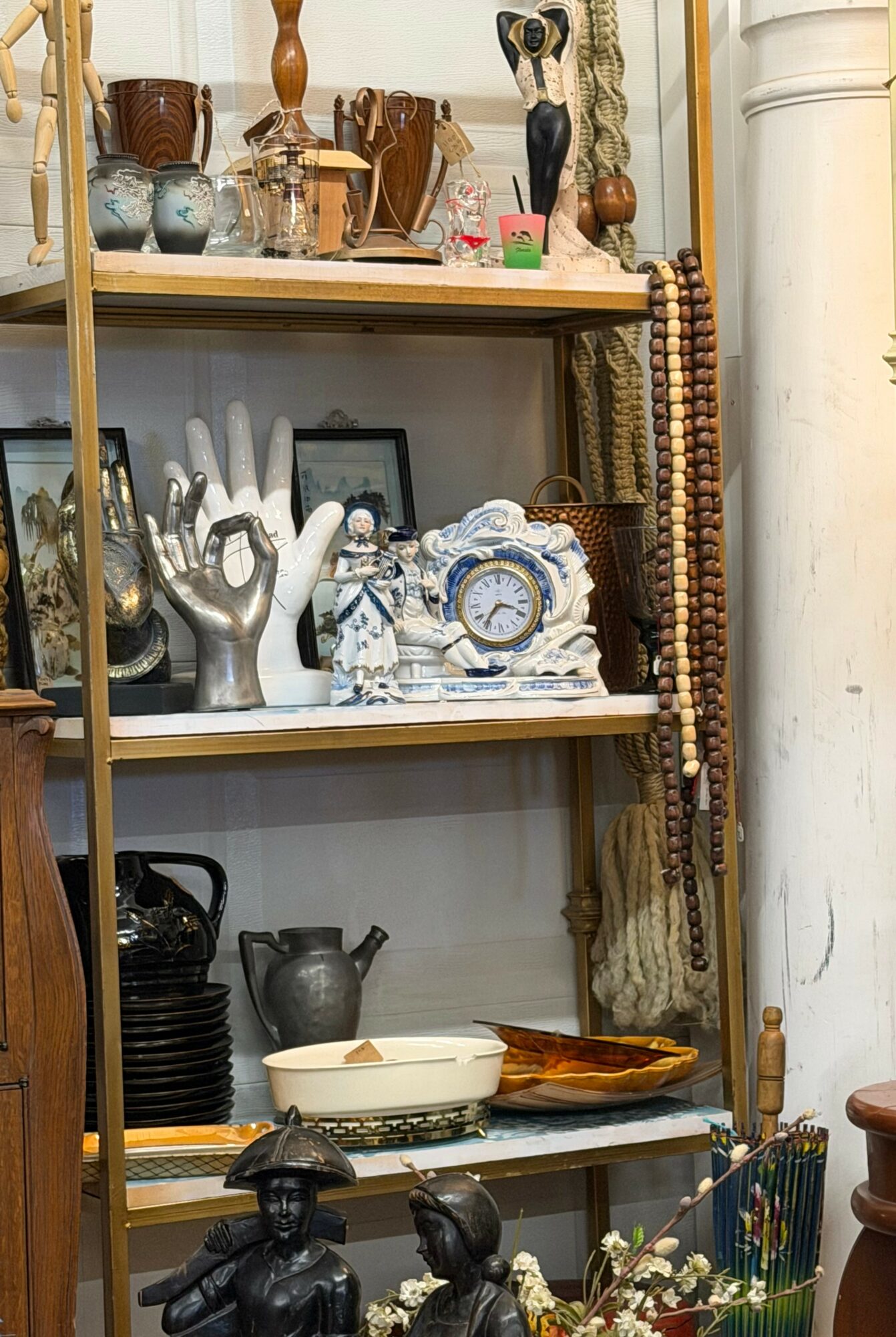 Shelves filled with decorative items, including hands, clocks, vases, and framed pictures, with a beaded curtain on the right side.