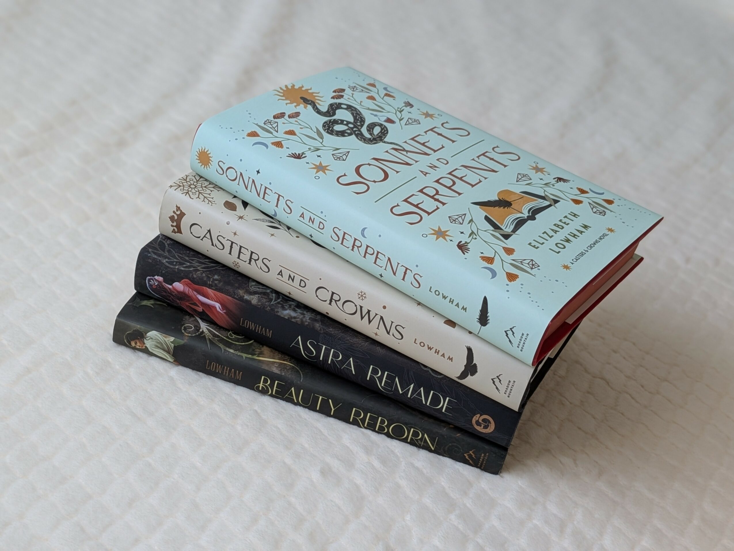 Stack of four books with colorful covers on a white textured surface.