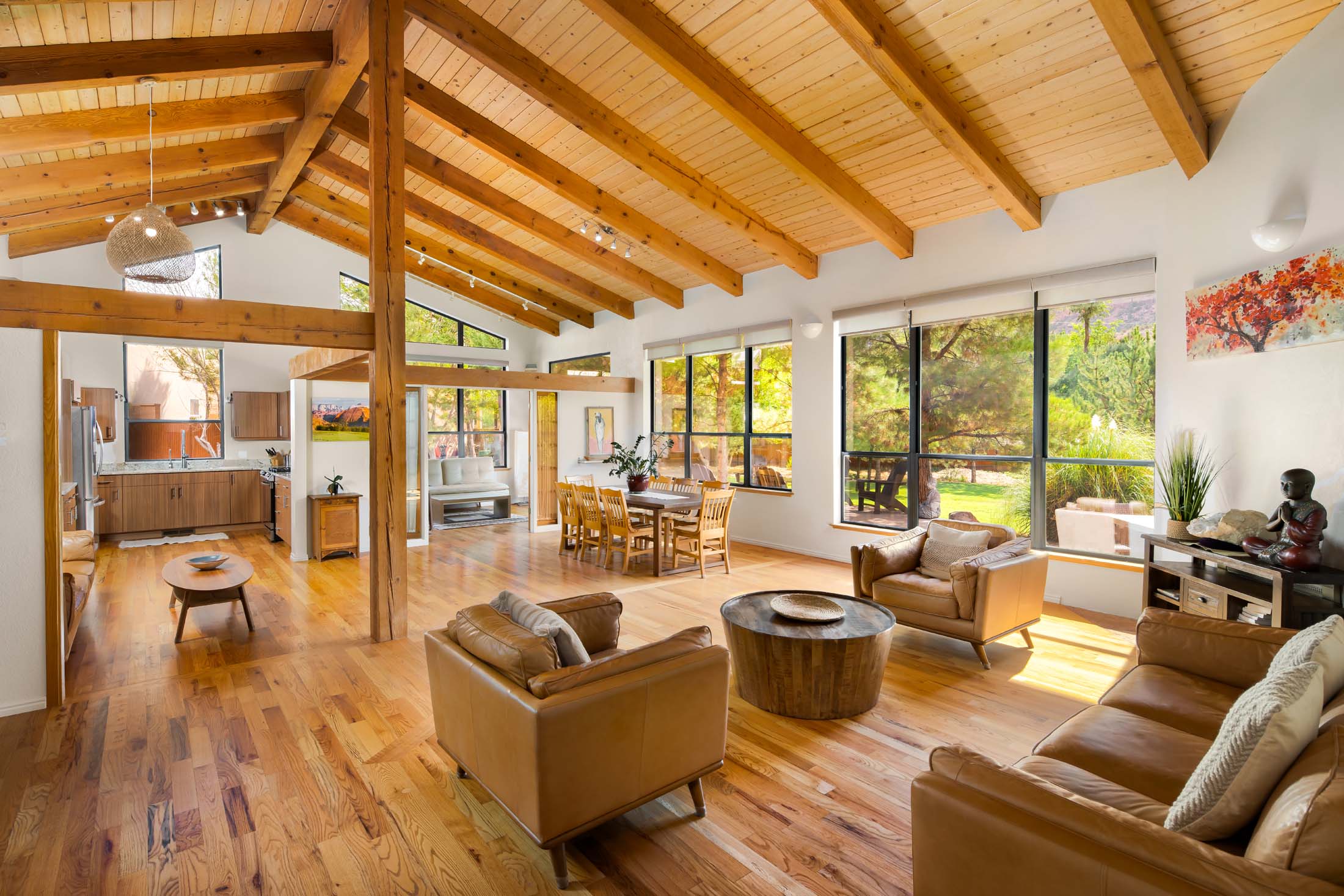 Spacious living room with large windows, wooden ceiling, and furniture including sofas and a coffee table.