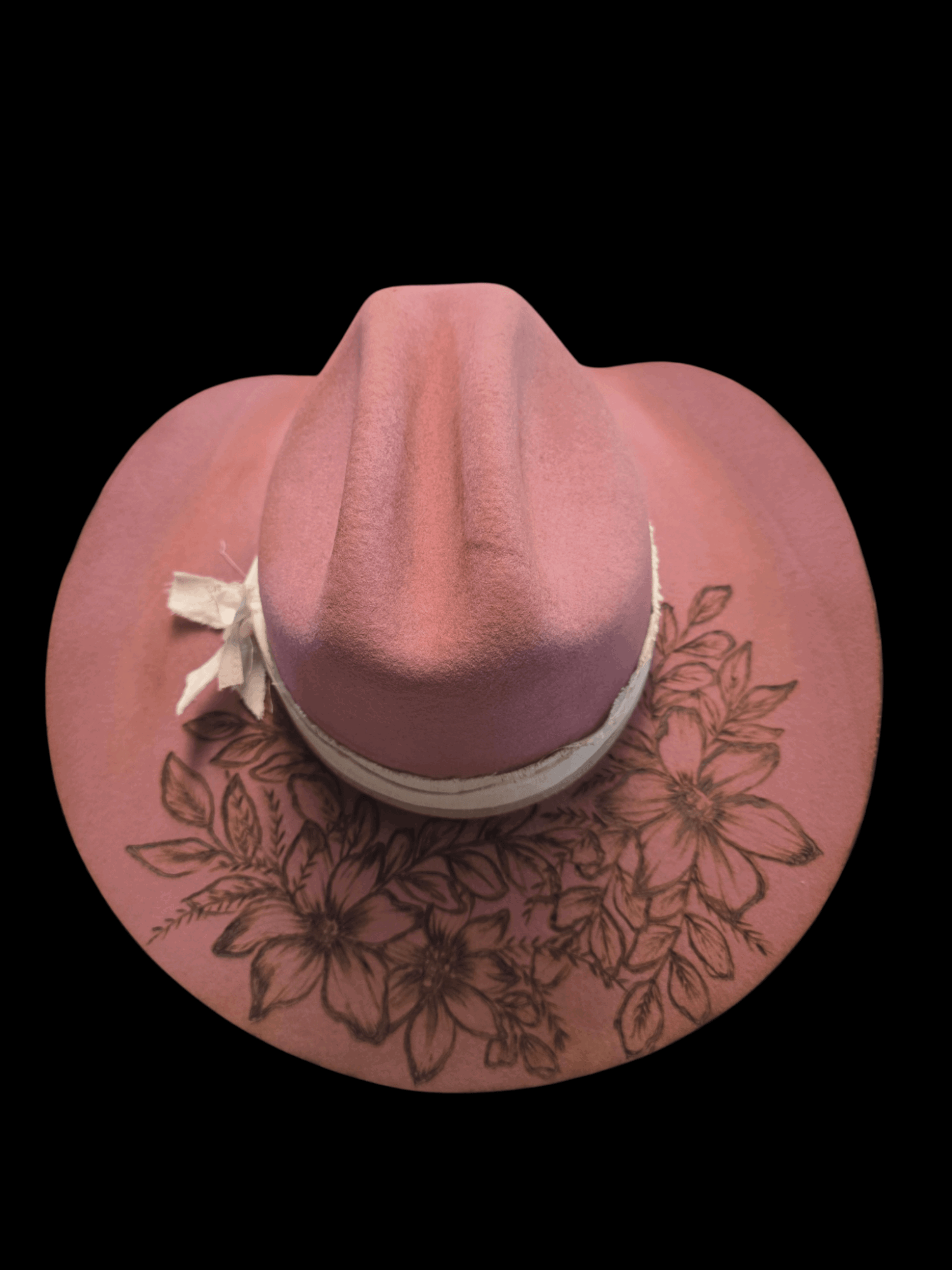 Pink wide-brimmed hat with a bow, decorated with floral embroidery, against a black background.