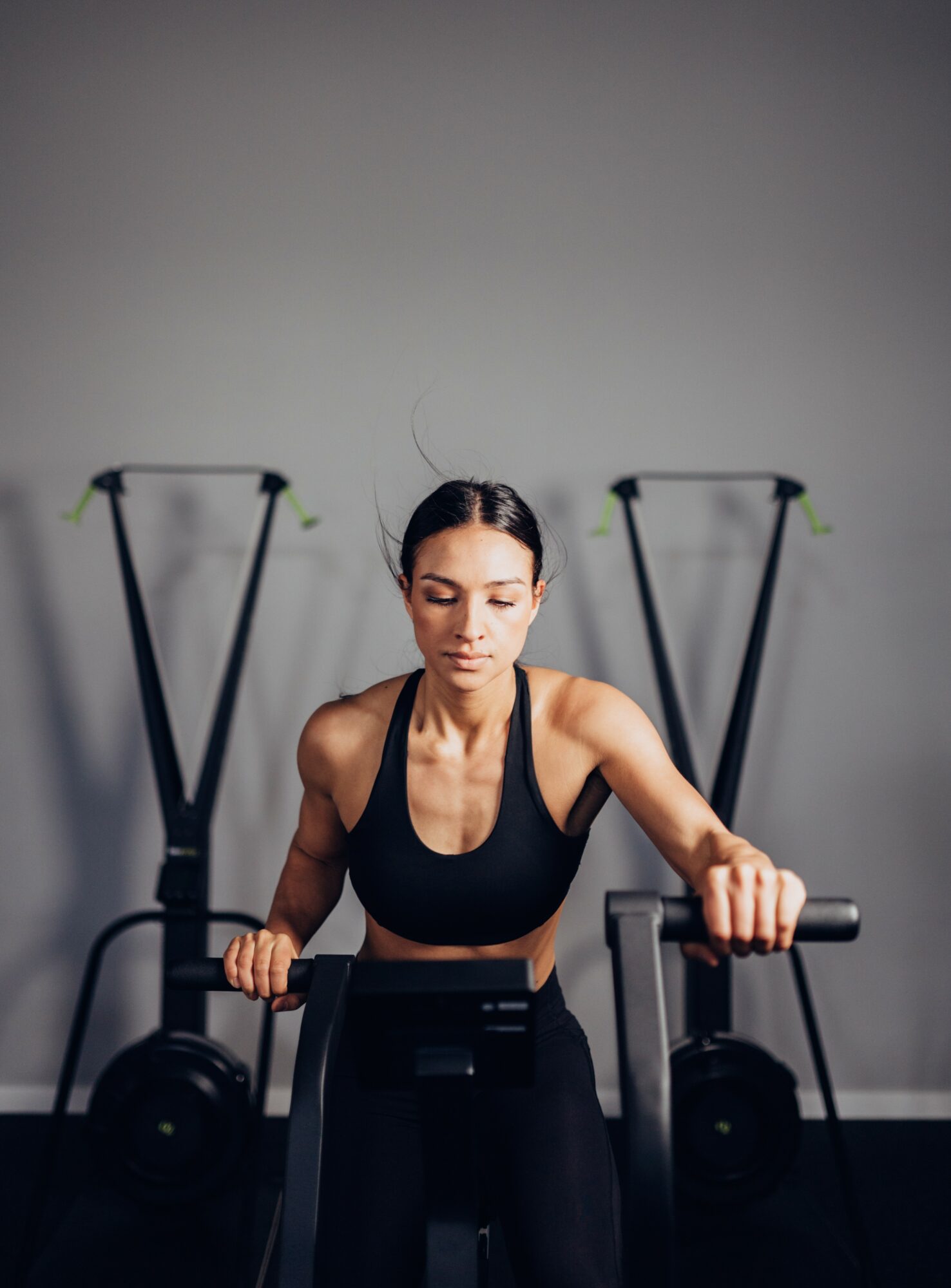 Woman in workout clothes using a rowing machine in a gym, with exercise equipment in the background.