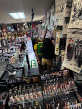 People shopping in a store with shelves of cosmetics and beauty products, some browsing and others at the checkout counter.