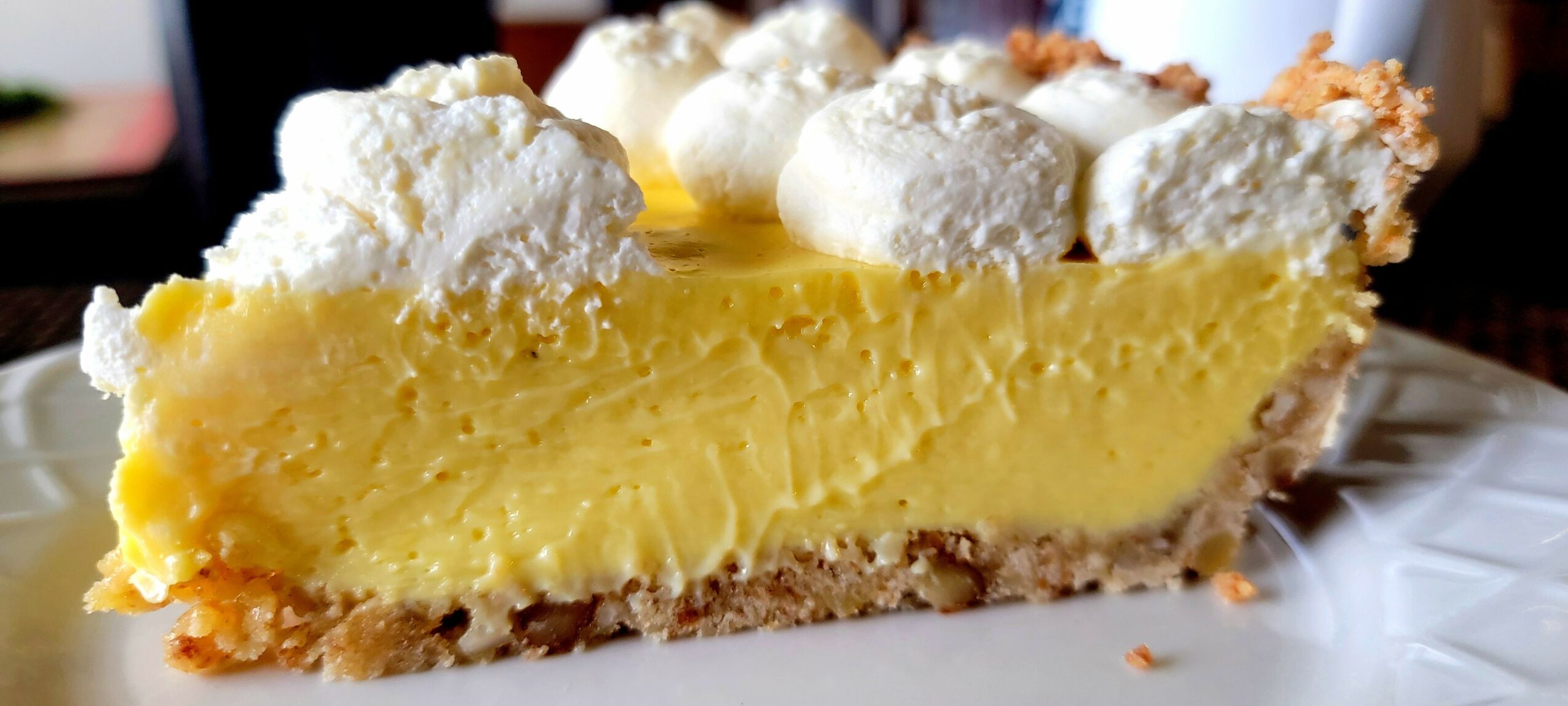 Slice of lemon cheesecake with whipped cream topping on a plate.