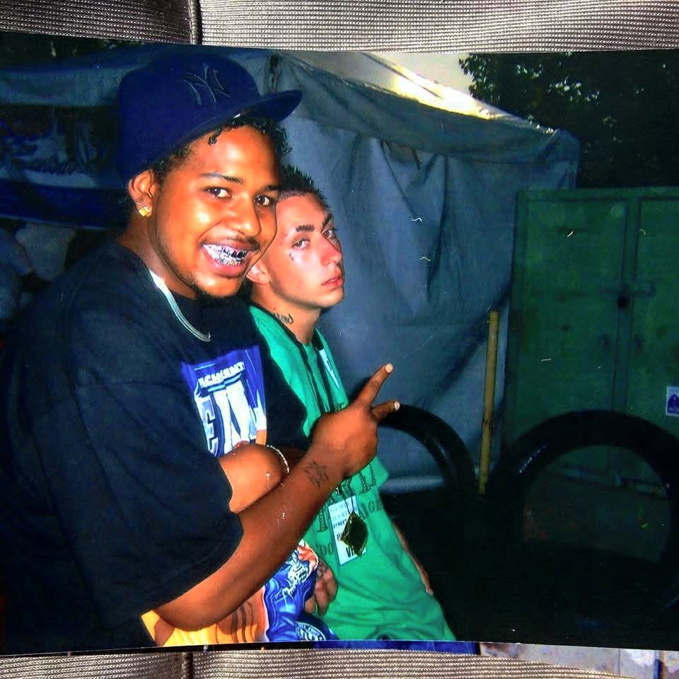 Two young women smiling, one wearing a blue cap and the other with long hair, outdoors at night.