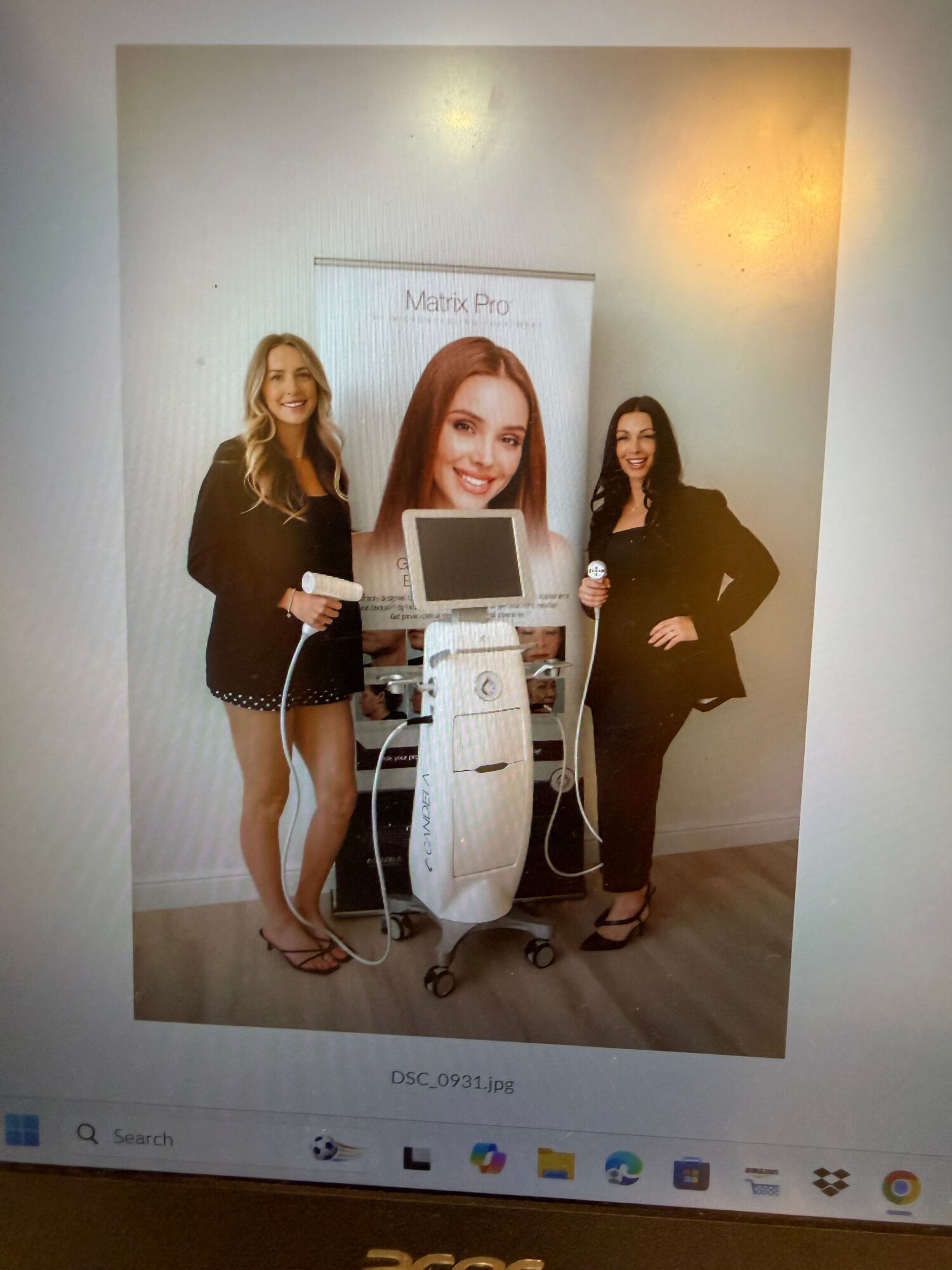 Three people pose beside a computer display showing a website, with a vertical row of icons along the screen edge.