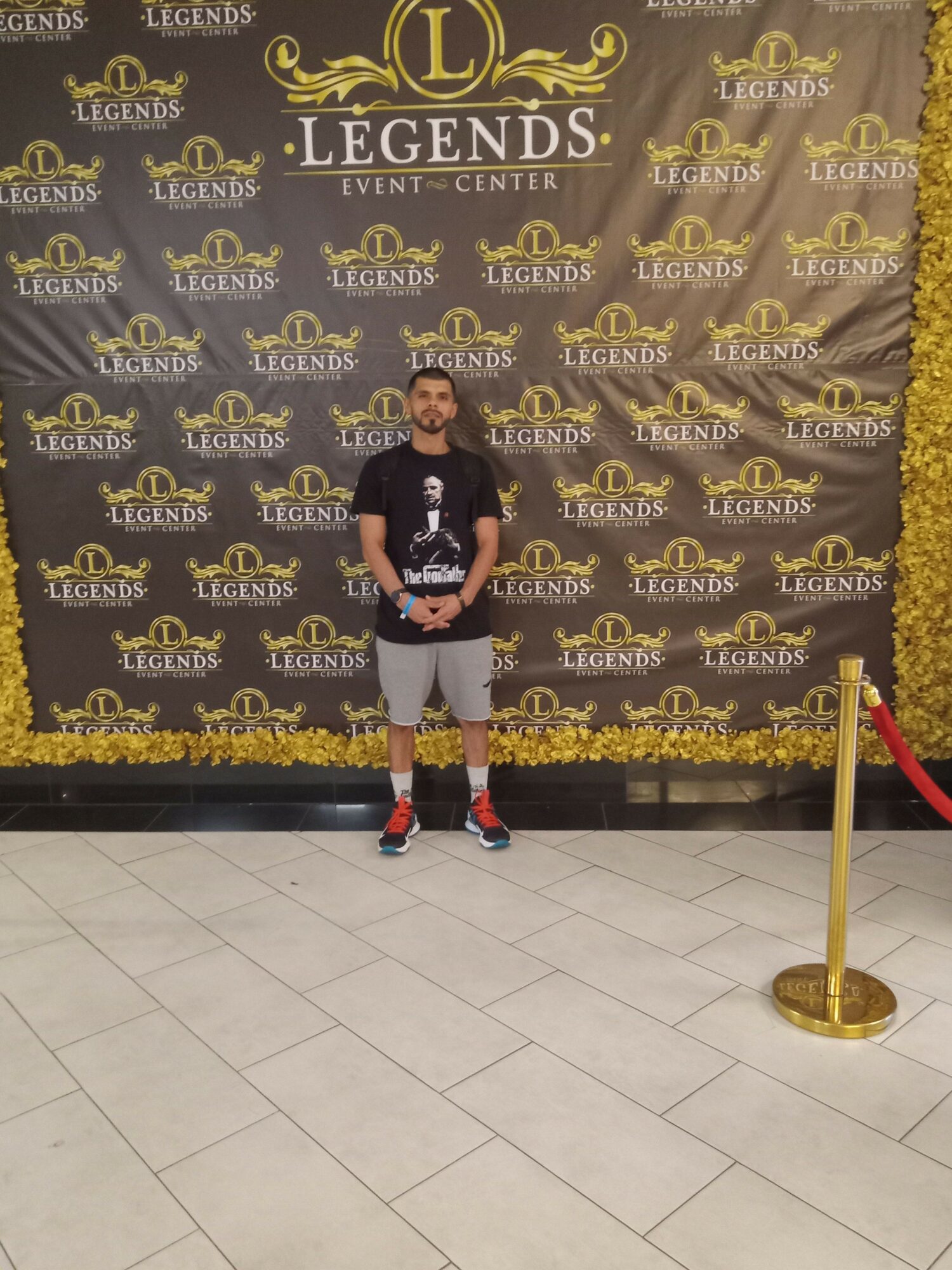 Person standing in front of a black and gold backdrop with