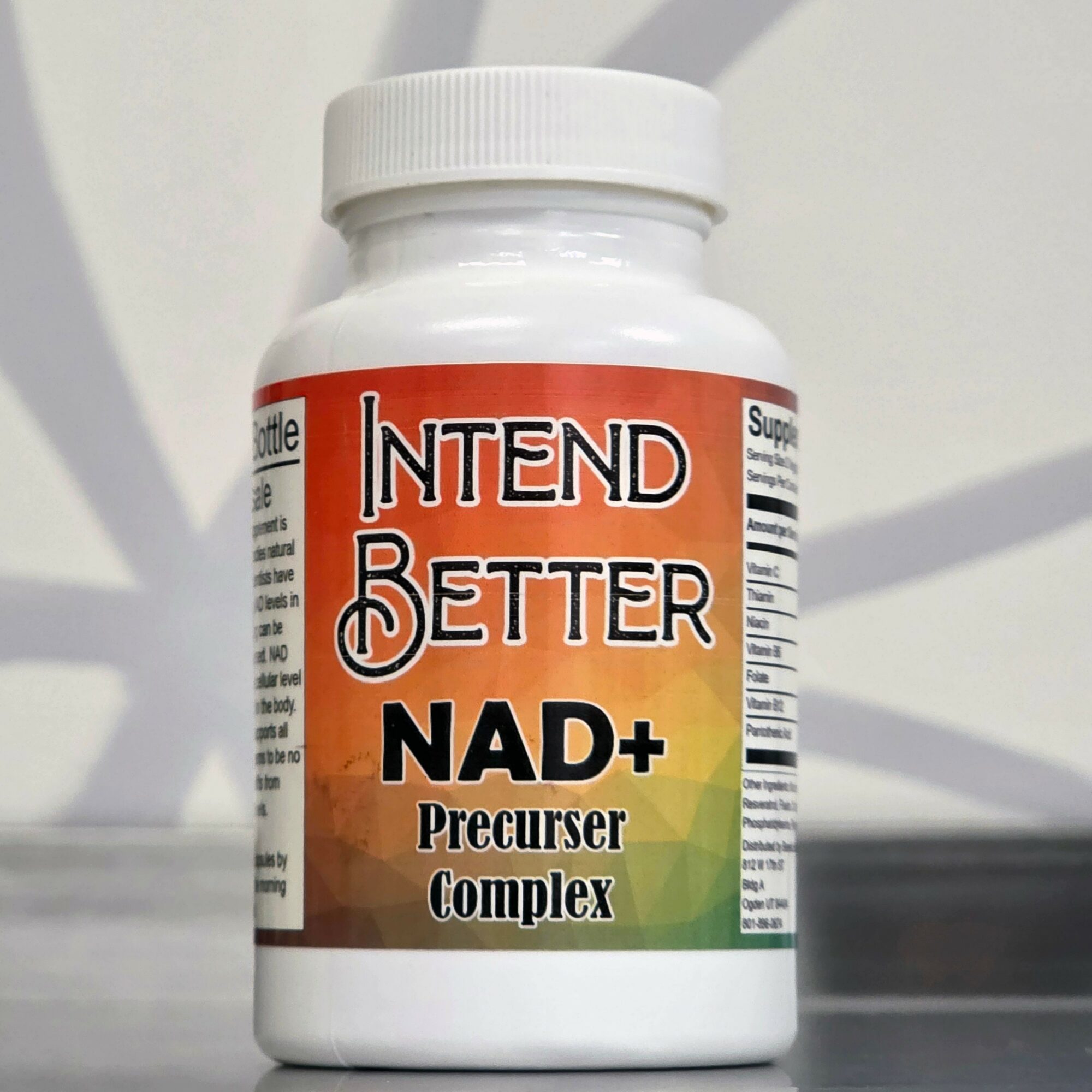 Bottle labeled 'INTEND BETTER NAD+ Precursor Complex' with a white cap and colorful label, on a surface with a light background.