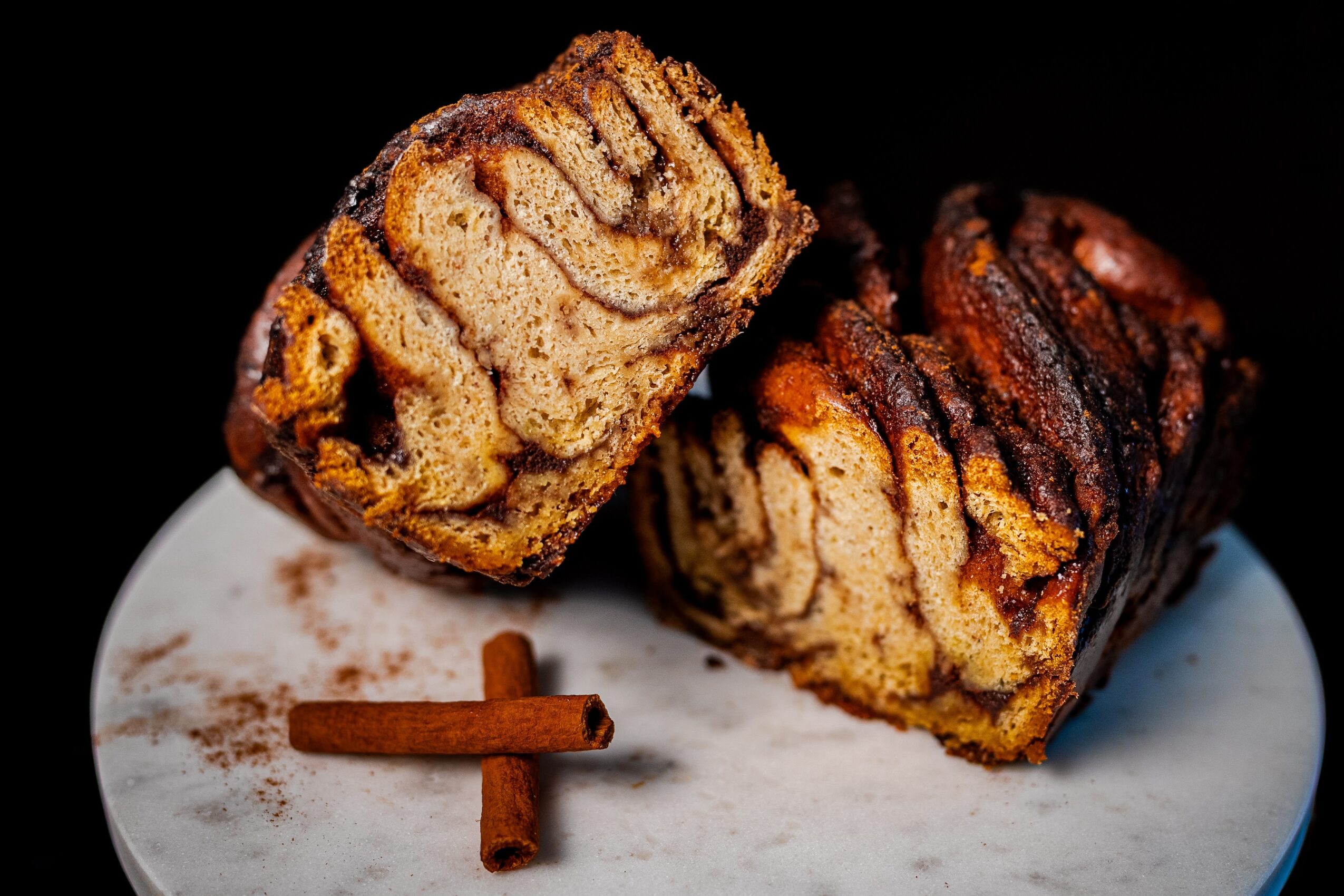 Two slices of marbled bread on a white plate with a cinnamon stick.