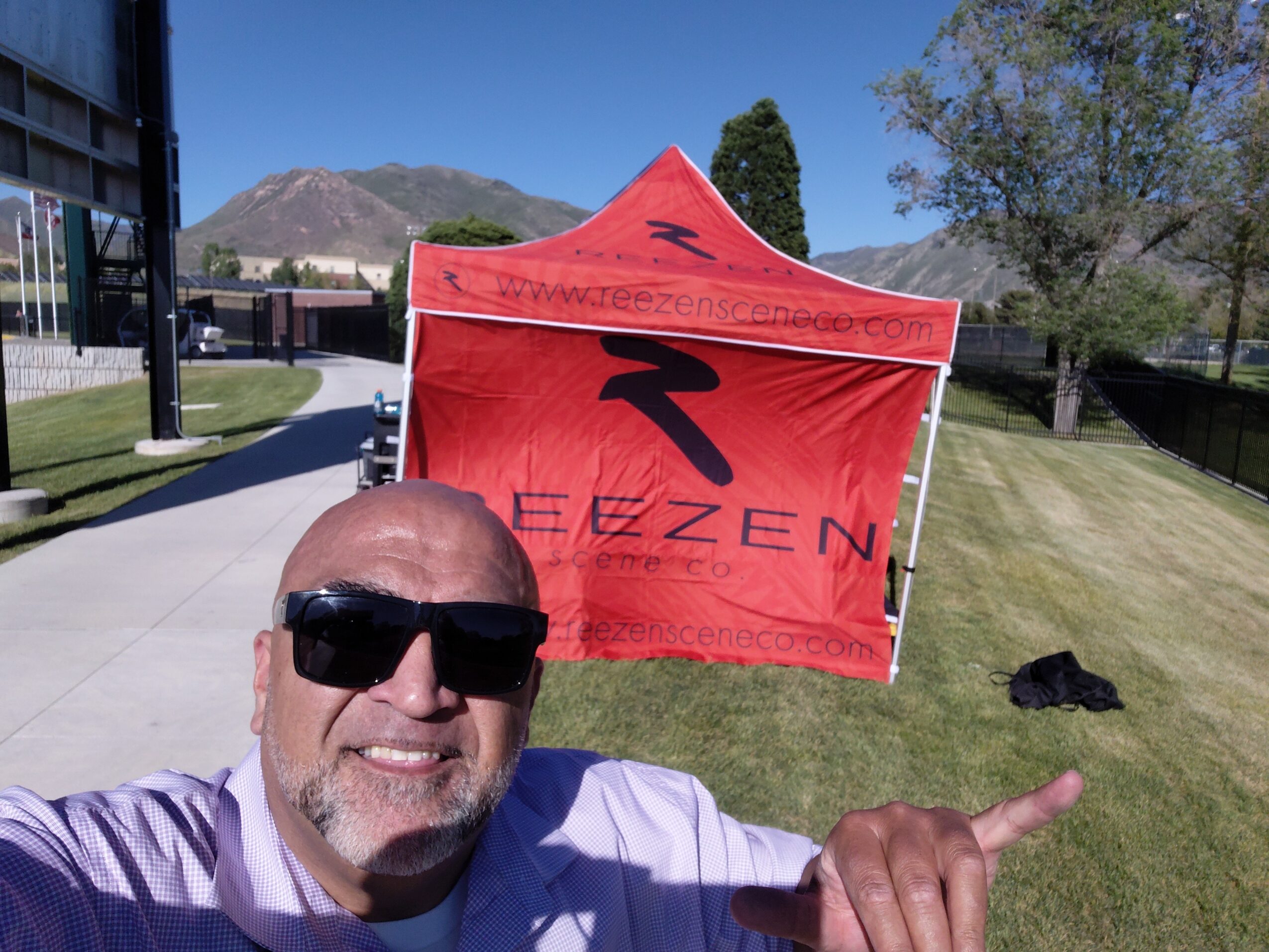 Person wearing sunglasses poses in front of a red EZEN tent outdoors.
